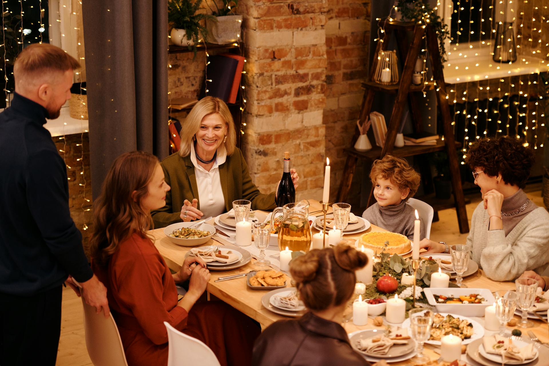 Une famille assise autour d'une table éclairée aux chandelles avec un festin de vacances | Source : Pexels