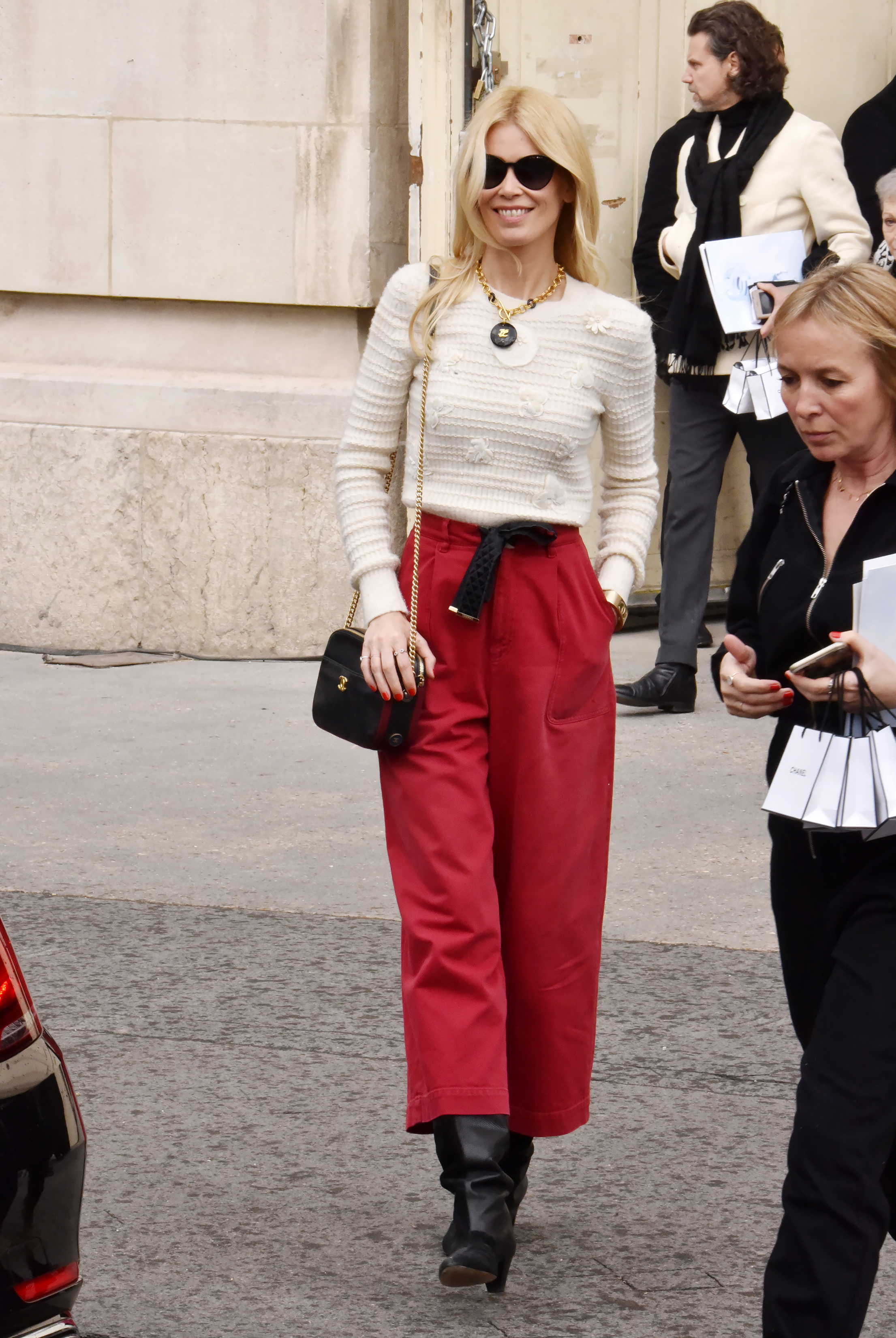 Claudia Schiffer fait son apparition au défilé Chanel Automne/Hiver de la Fashion Week de Paris, chic et naturelle dans un pantalon rouge vif et un pull texturé ivoire. Avec ses lunettes de soleil oversize et son collier imposant, elle incarne l'élégance moderne avec une touche parisienne.