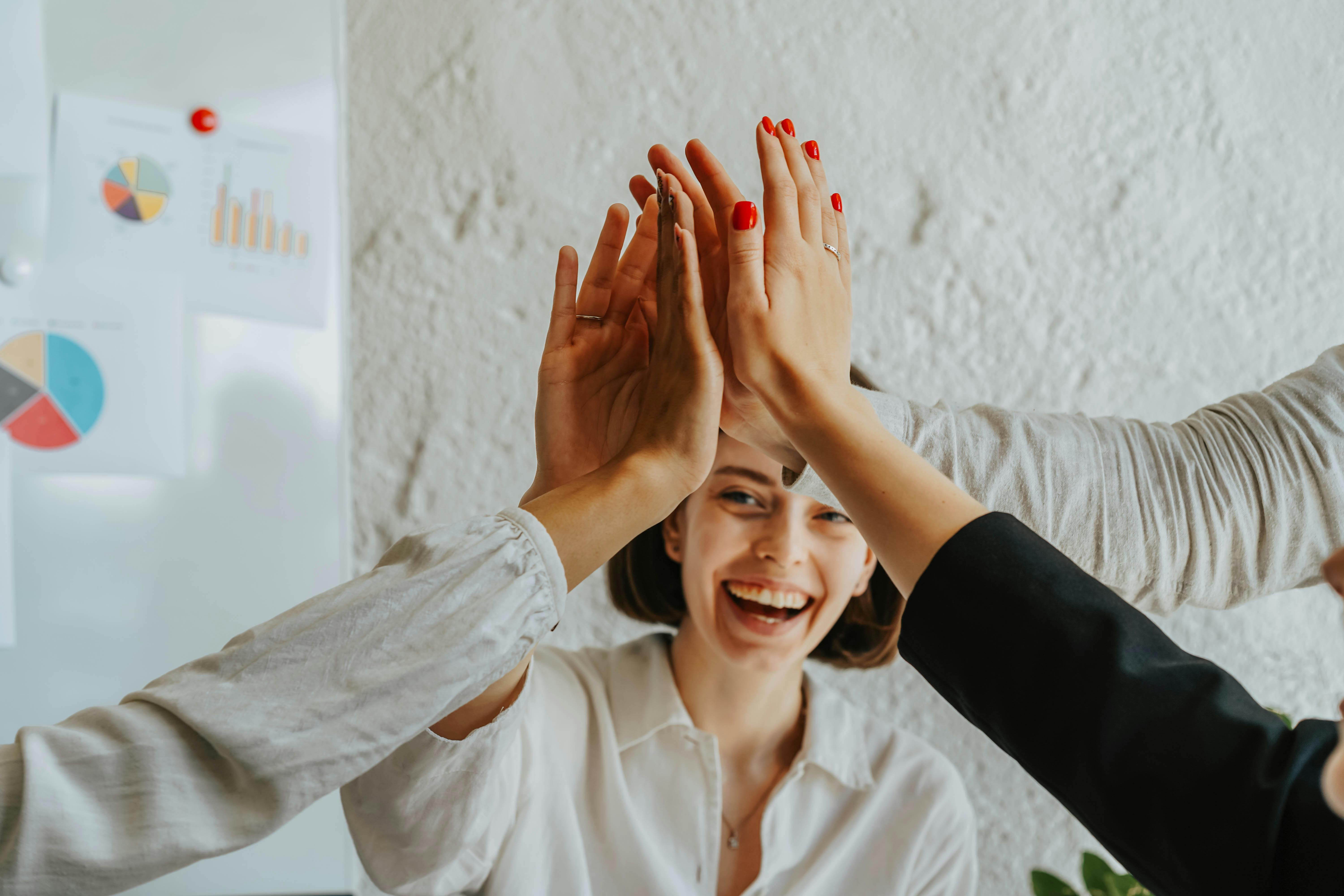 Un groupe de personnes heureuses partageant des high-five dans un bureau | Source : Pexels
