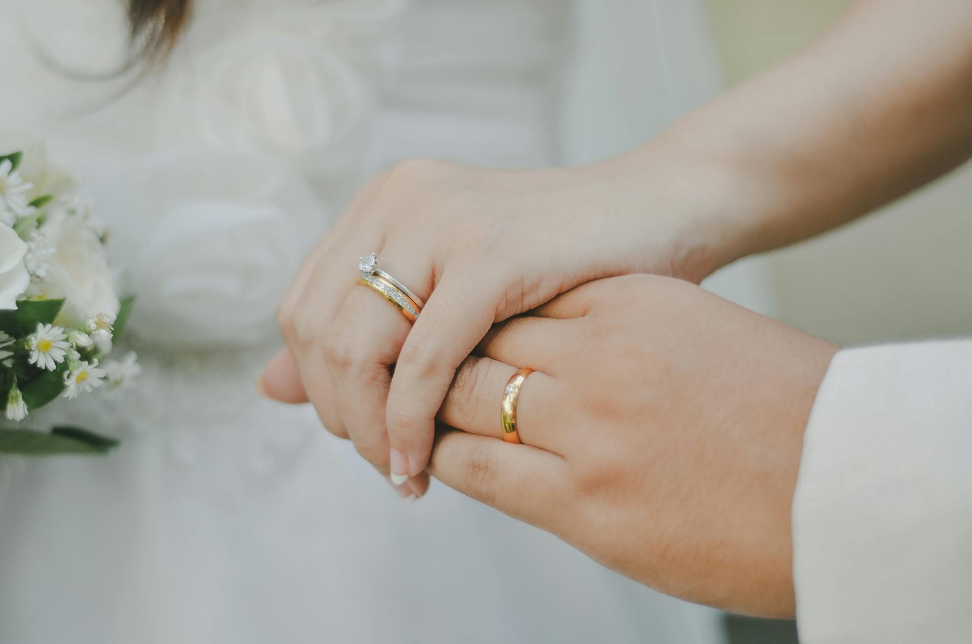 Une mariée et un marié se tenant par la main et montrant leurs alliances | Source : Pexels