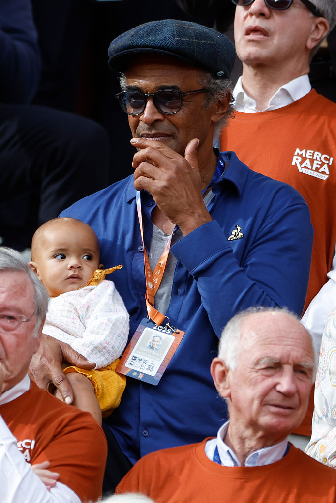 Yannick Noah tenant sa fille nouveau-née lors de la cérémonie en l'honneur de la carrière de Rafael Nadal et des 14 titres remportés sur les courts en terre battue parisiens lors de la première journée de l'Open de France 2025 I Source : Getty Images