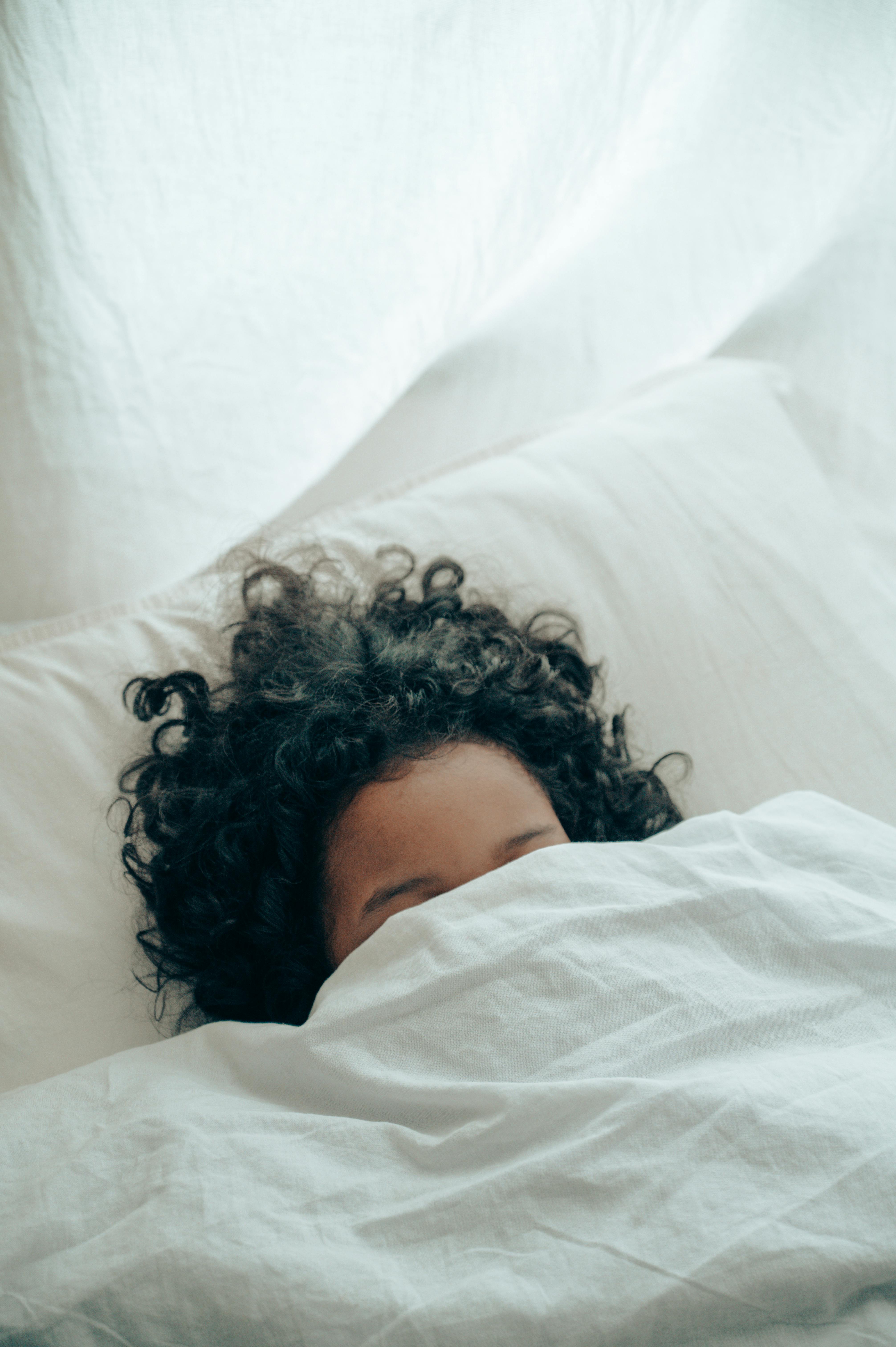 Une personne dormant sous une couverture | Source : Pexels