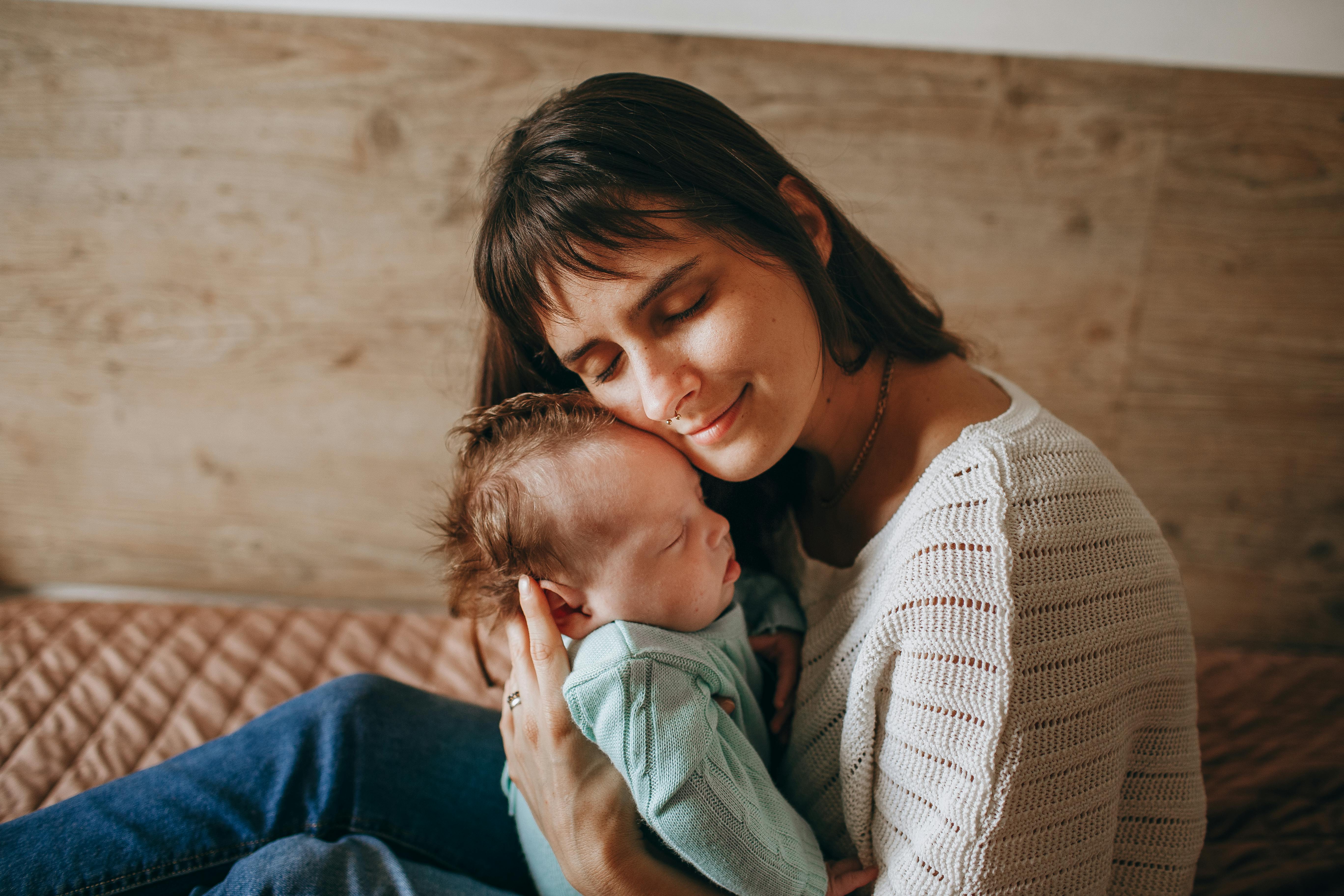 Une femme qui sourit tout en câlinant un bébé | Source : Pexels