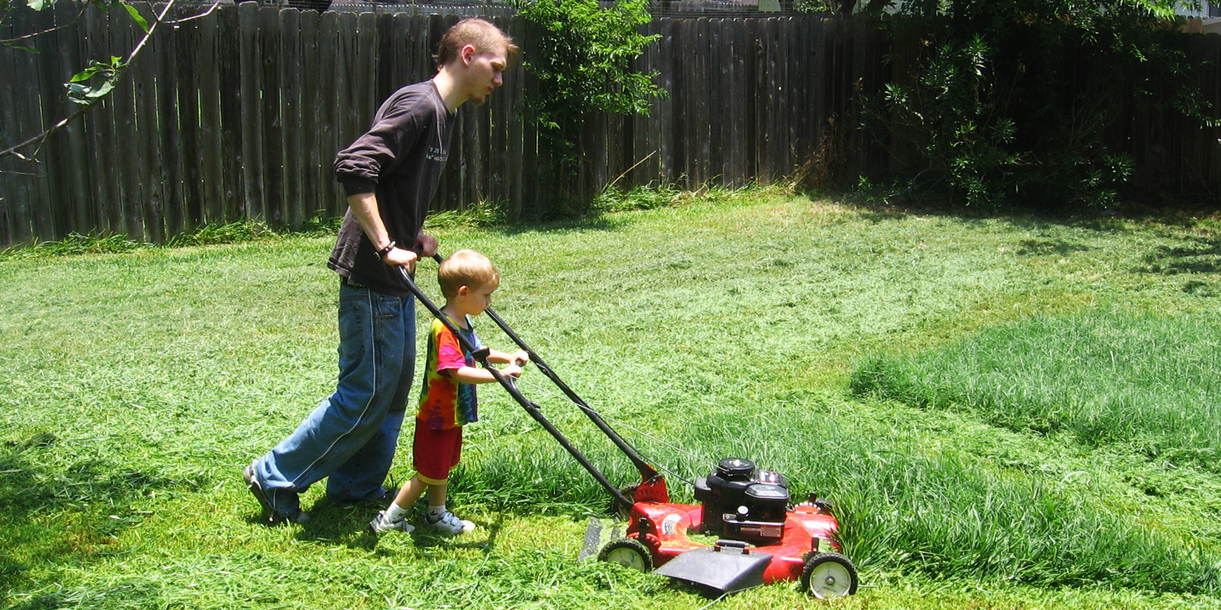 Un homme et son fils en train de tondre la pelouse | Source : Flickr