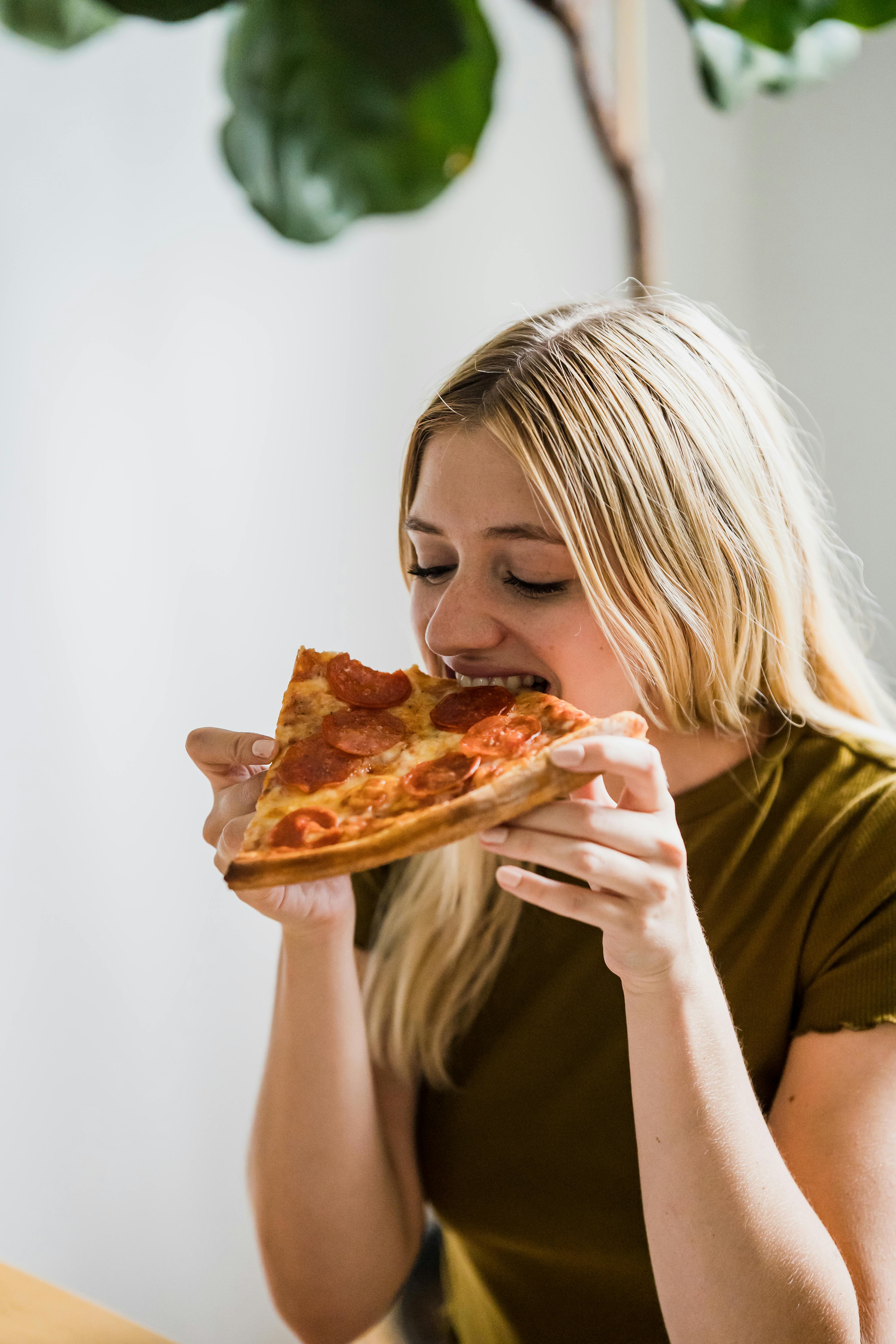 Une femme heureuse mangeant une pizza | Source : Pexels