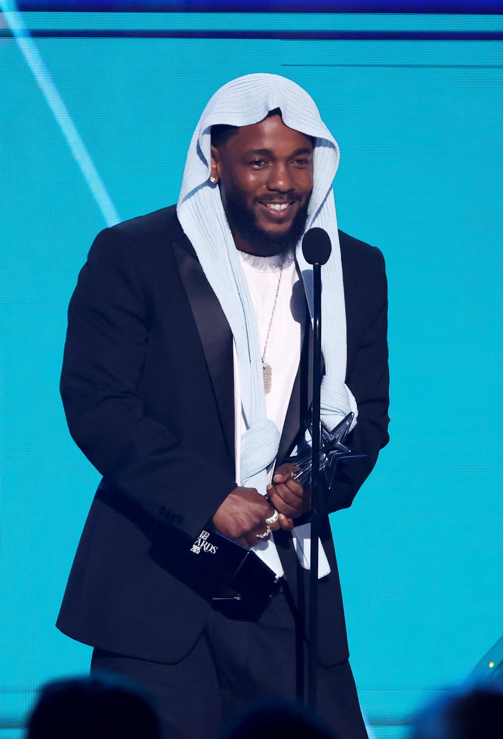 Kendrick Lamar rayonne sur scène alors qu'il reçoit le prix de l'album de l'année pour "GNX" lors des BET Awards 2025, organisés au Peacock Theater. Le look saisissant et le sourire sincère du rappeur ont illuminé la salle, tandis que les fans éclataient en applaudissements.