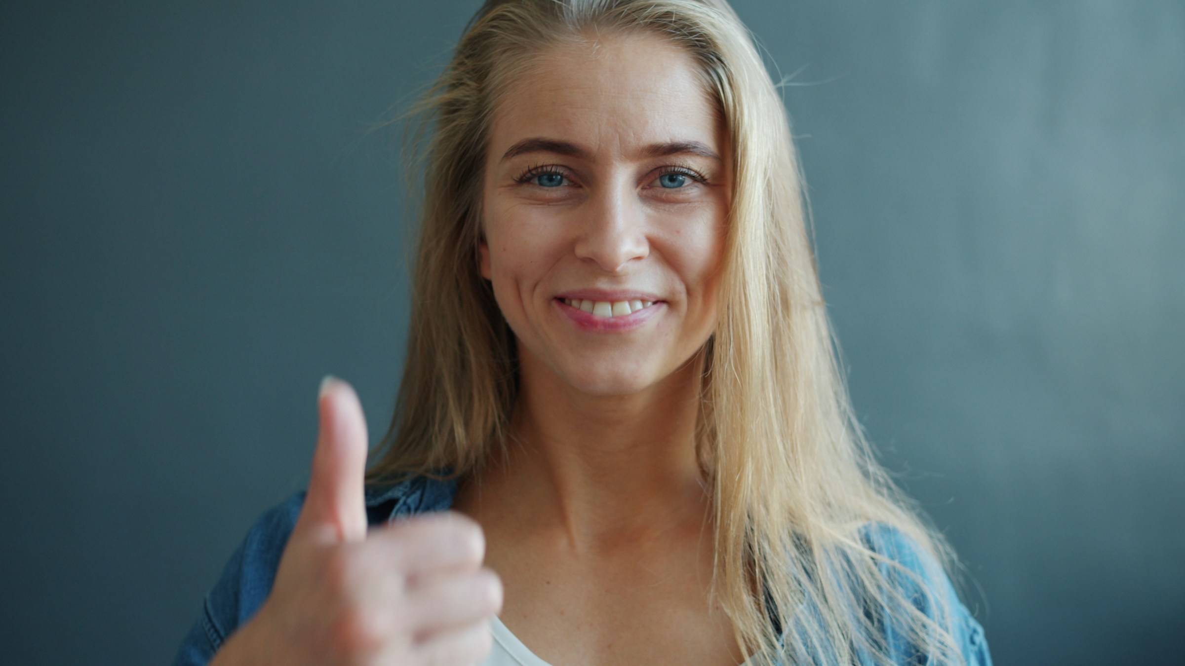Une femme souriante montrant un signe de pouce levé | Source : Unsplash