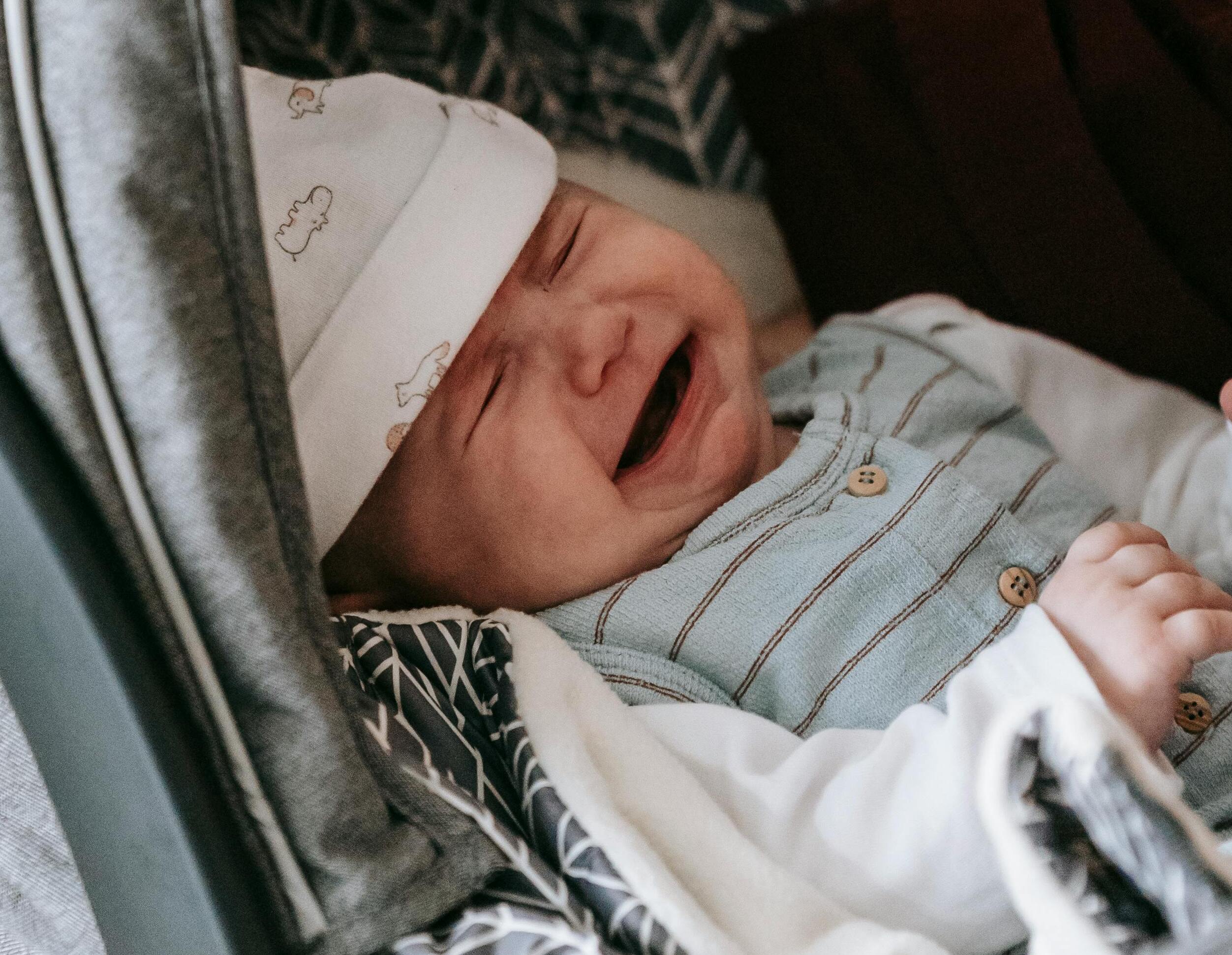 Un bébé avec un bonnet blanc en train de pleurer | Source : Pexels