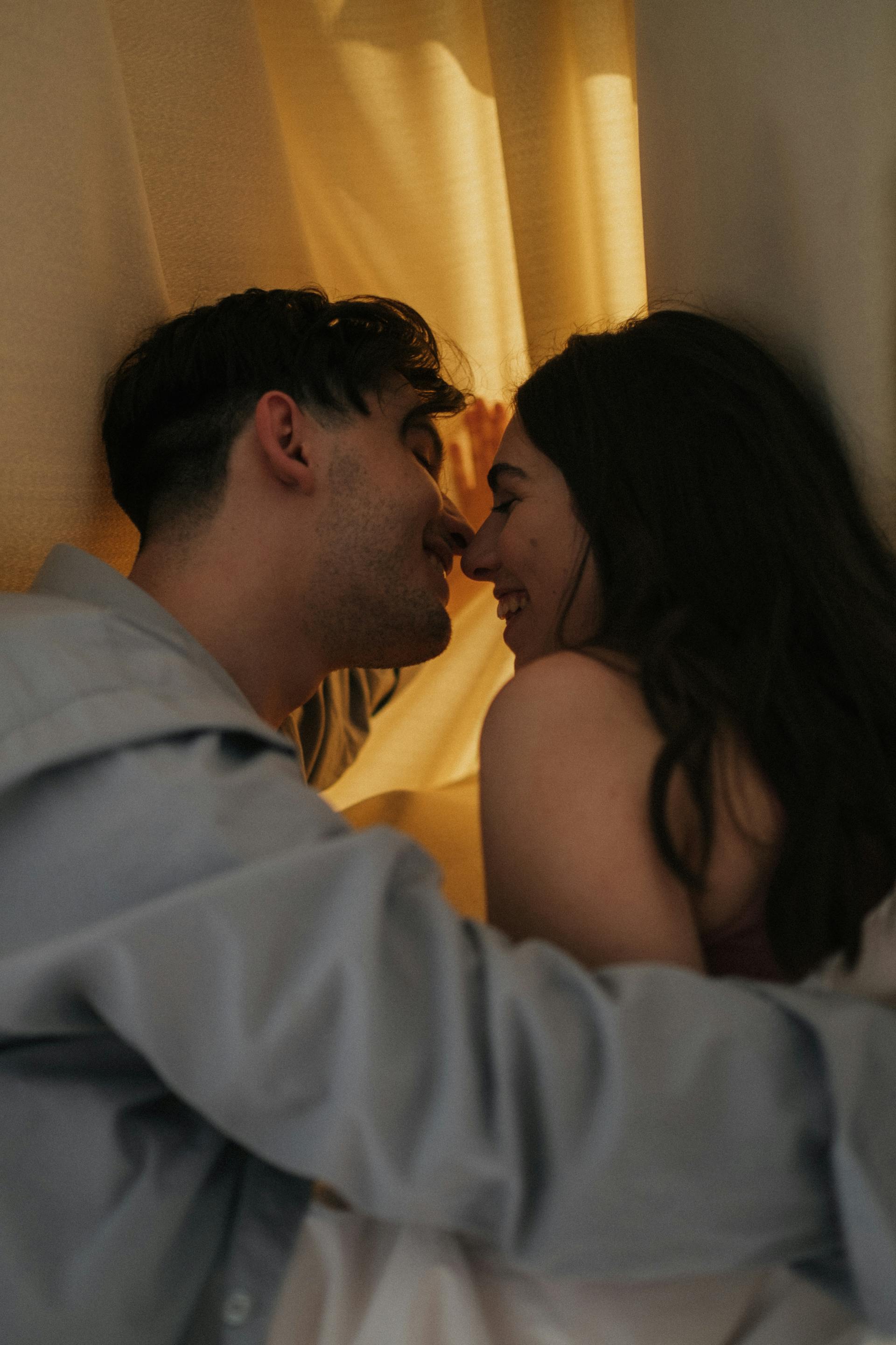 Un couple heureux s'embrassant derrière une draperie | Source : Pexels