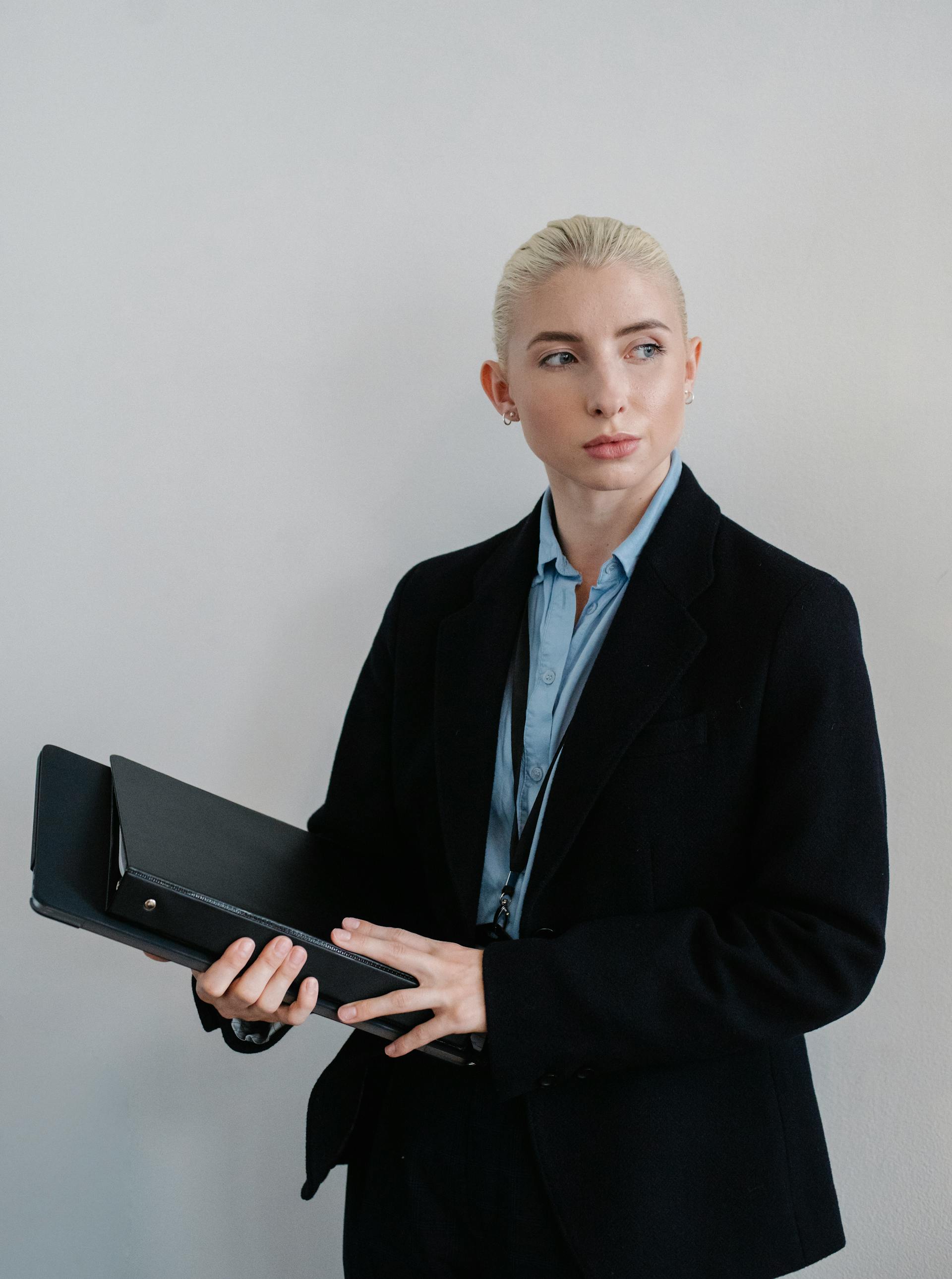 Une femme vêtue d'un manteau noir portant des dossiers | Source : Pexels