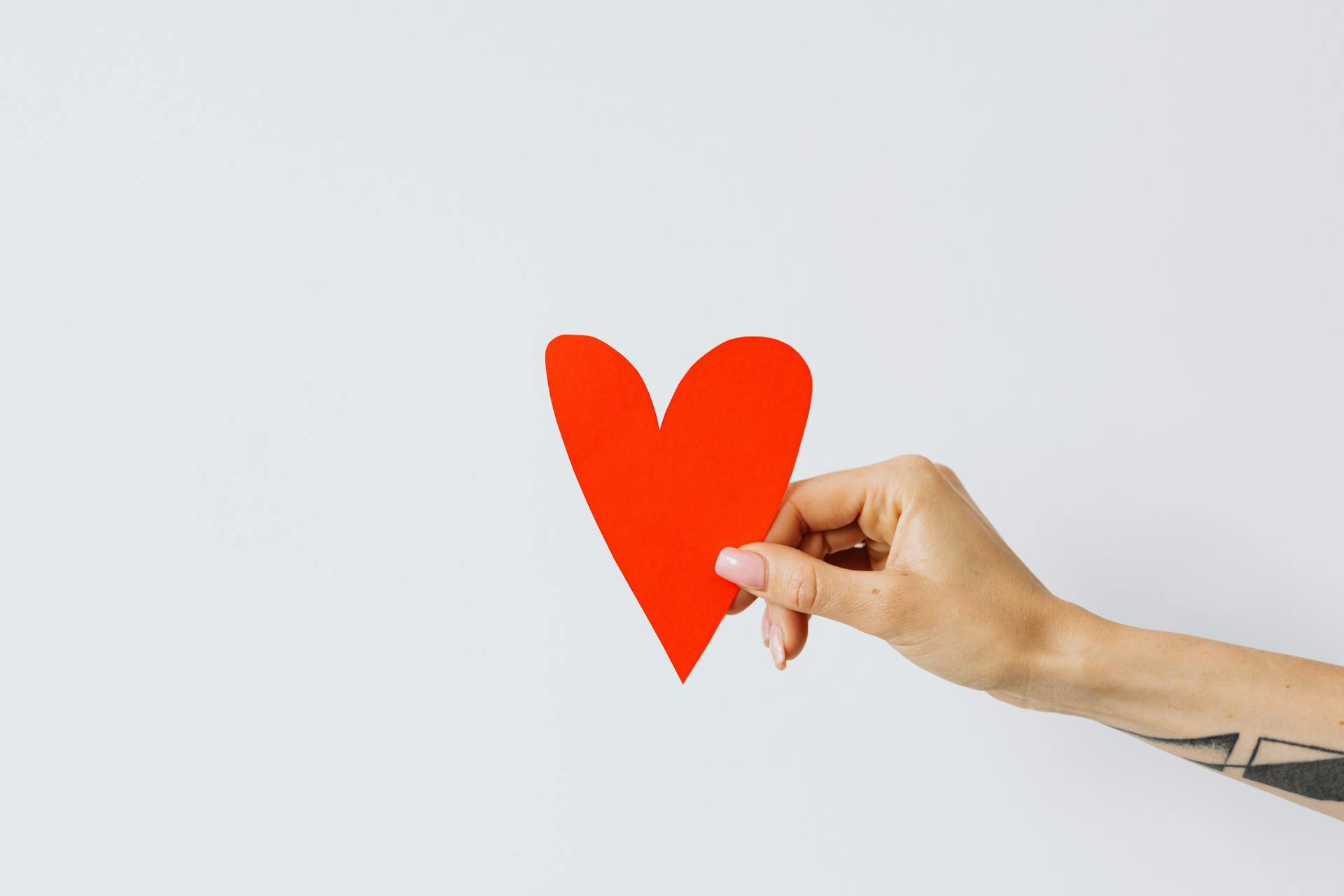Une femme tenant un cœur en papier rouge | Source : Pexels