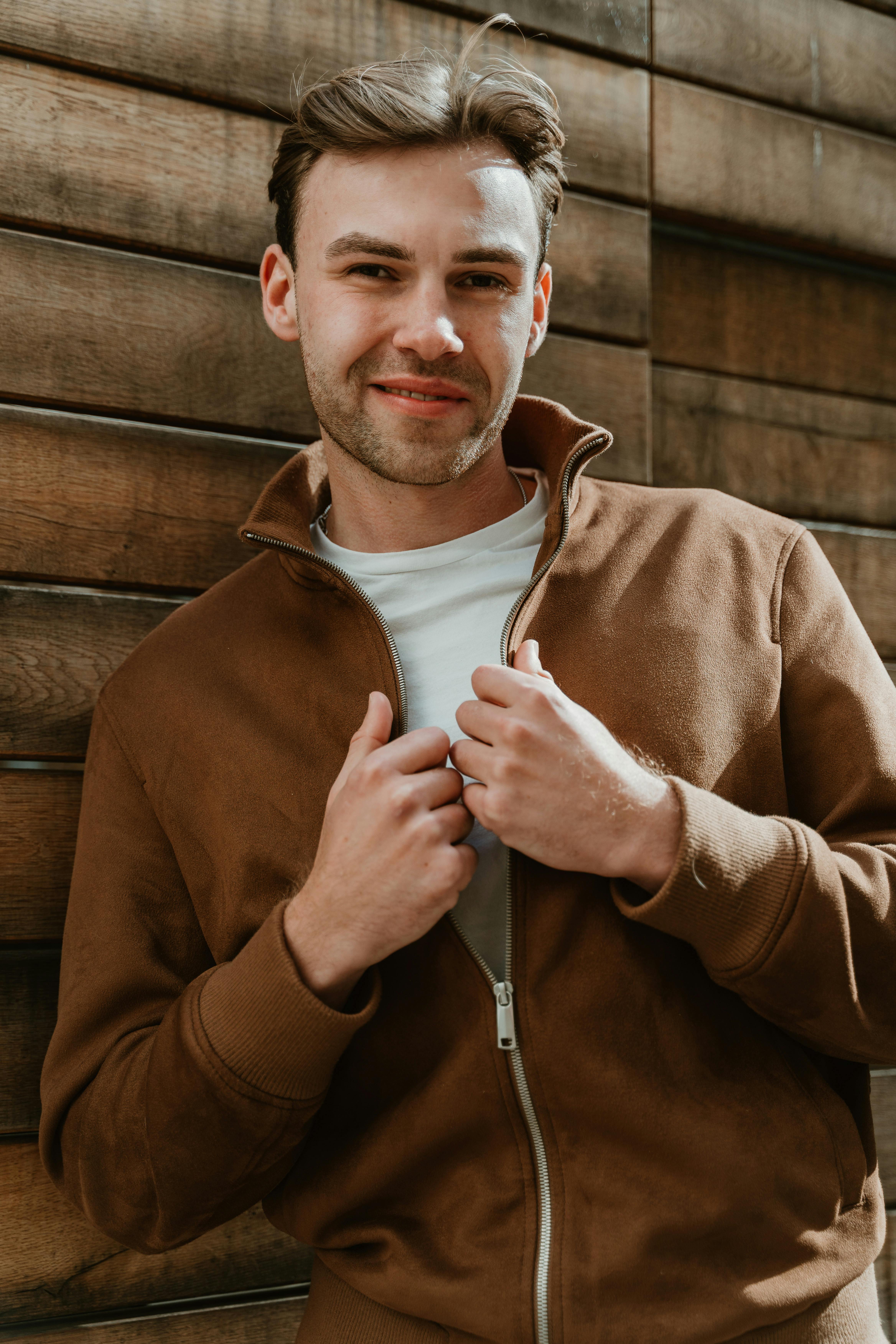 Un jeune homme souriant vêtu d'une veste marron | Source : Pexels