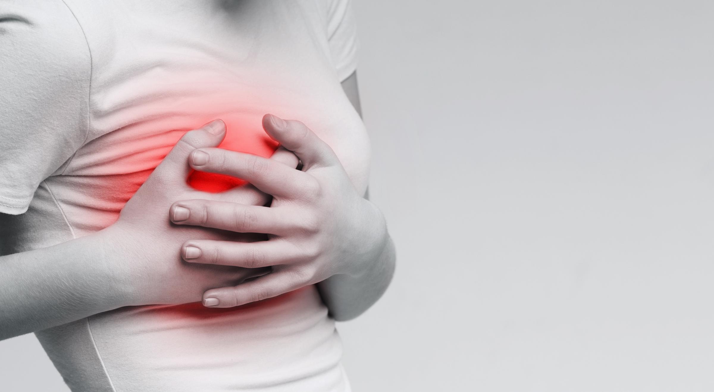 Une femme se serre la poitrine, indiquant une douleur thoracique soudaine - un symptôme potentiel nécessitant une évaluation médicale | Source : Getty Images