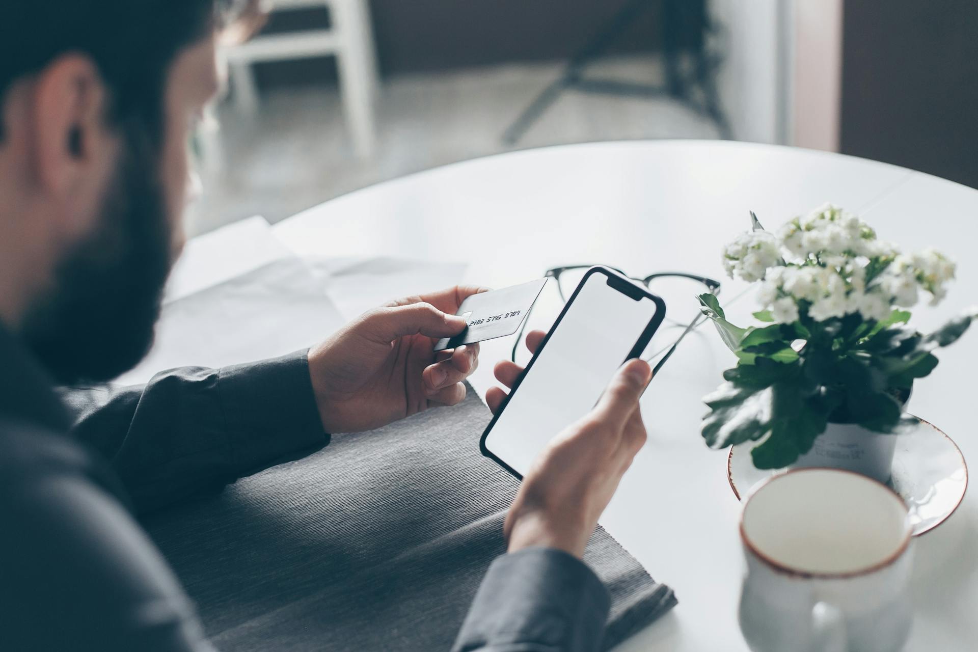 Un homme tenant une carte bancaire et un téléphone portable | Source : Pexels
