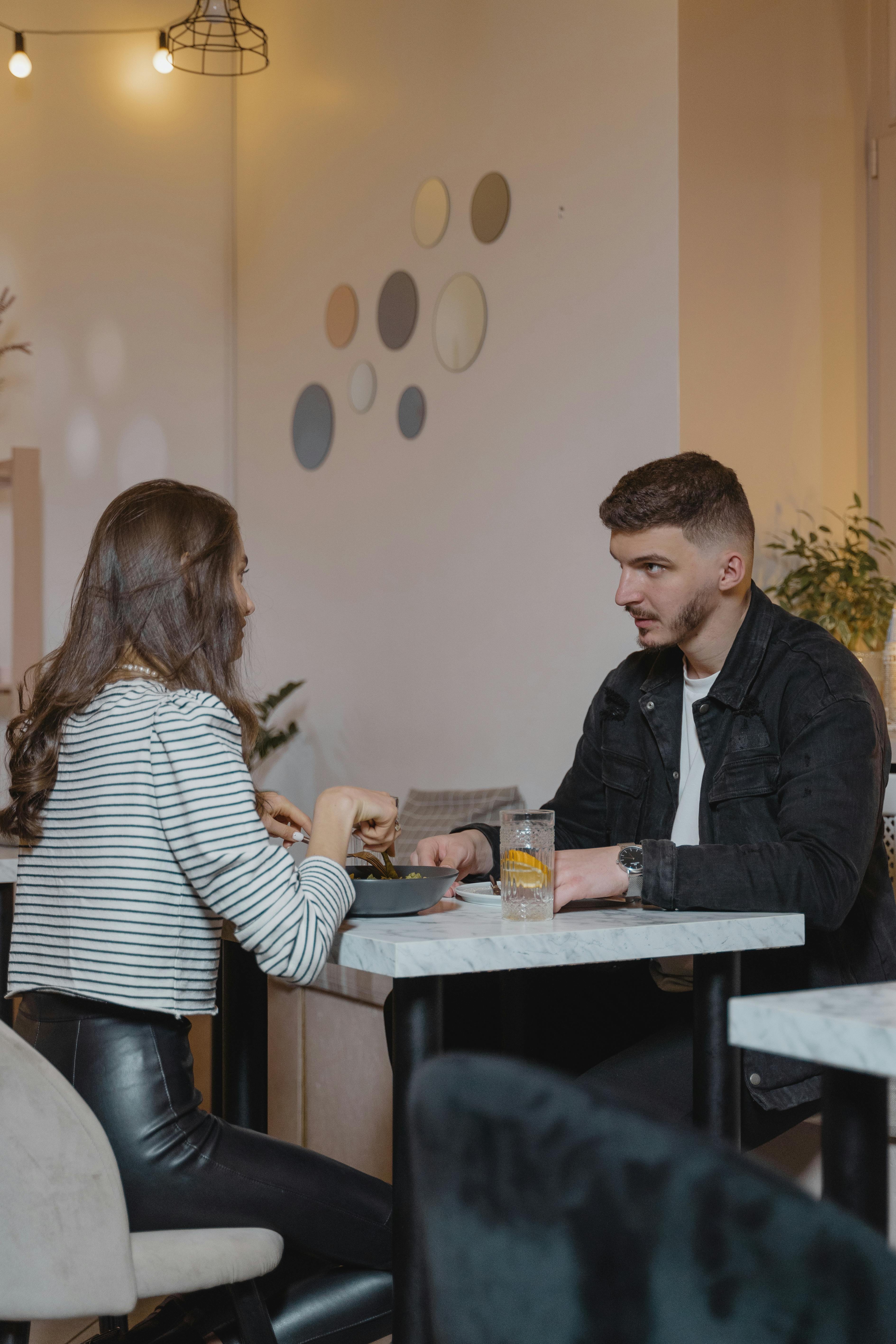 Un homme et une femme en train de discuter tout en mangeant | Source : Pexels