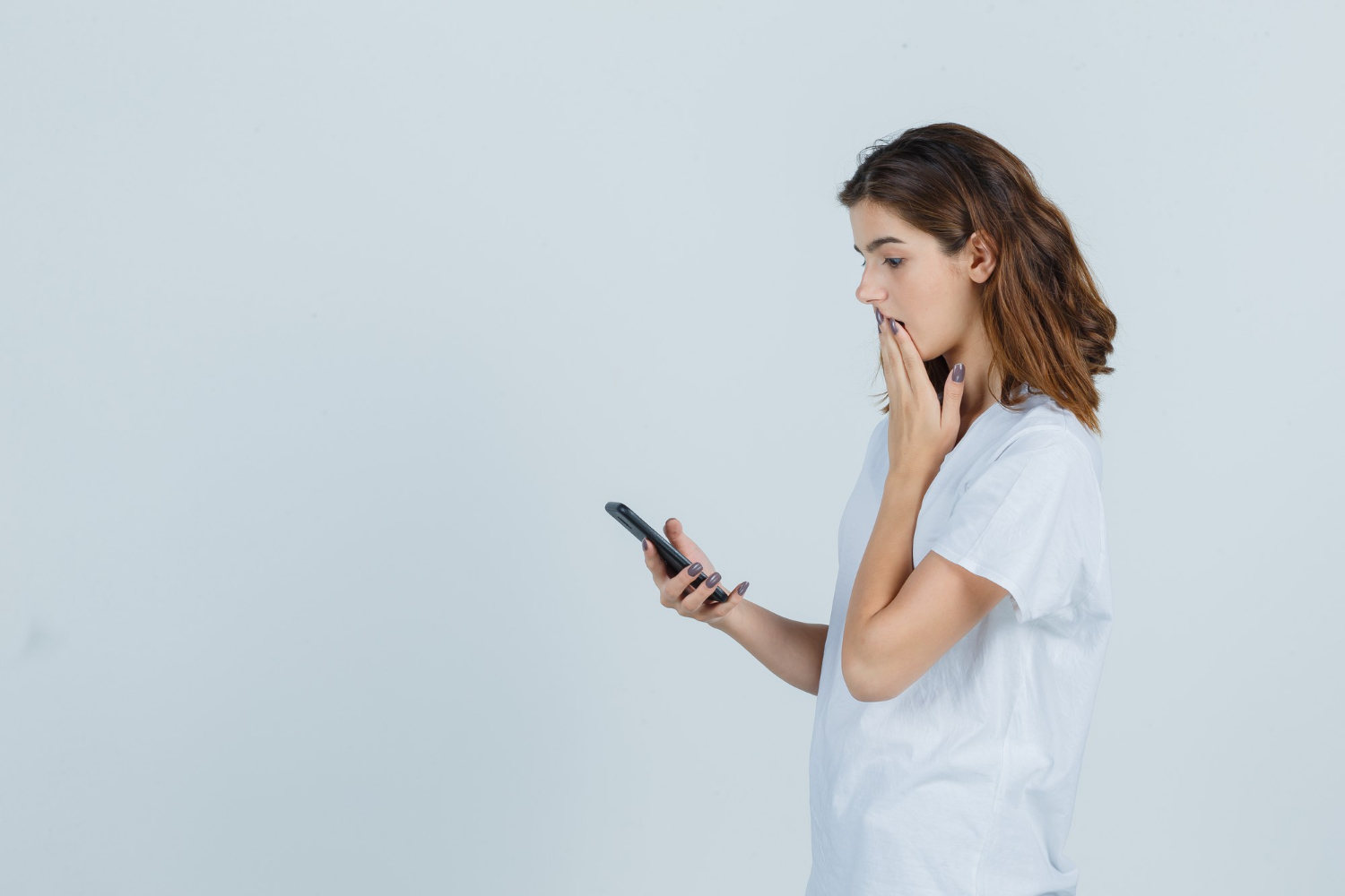 Une femme inquiète qui regarde fixement son téléphone | Source : Freepik