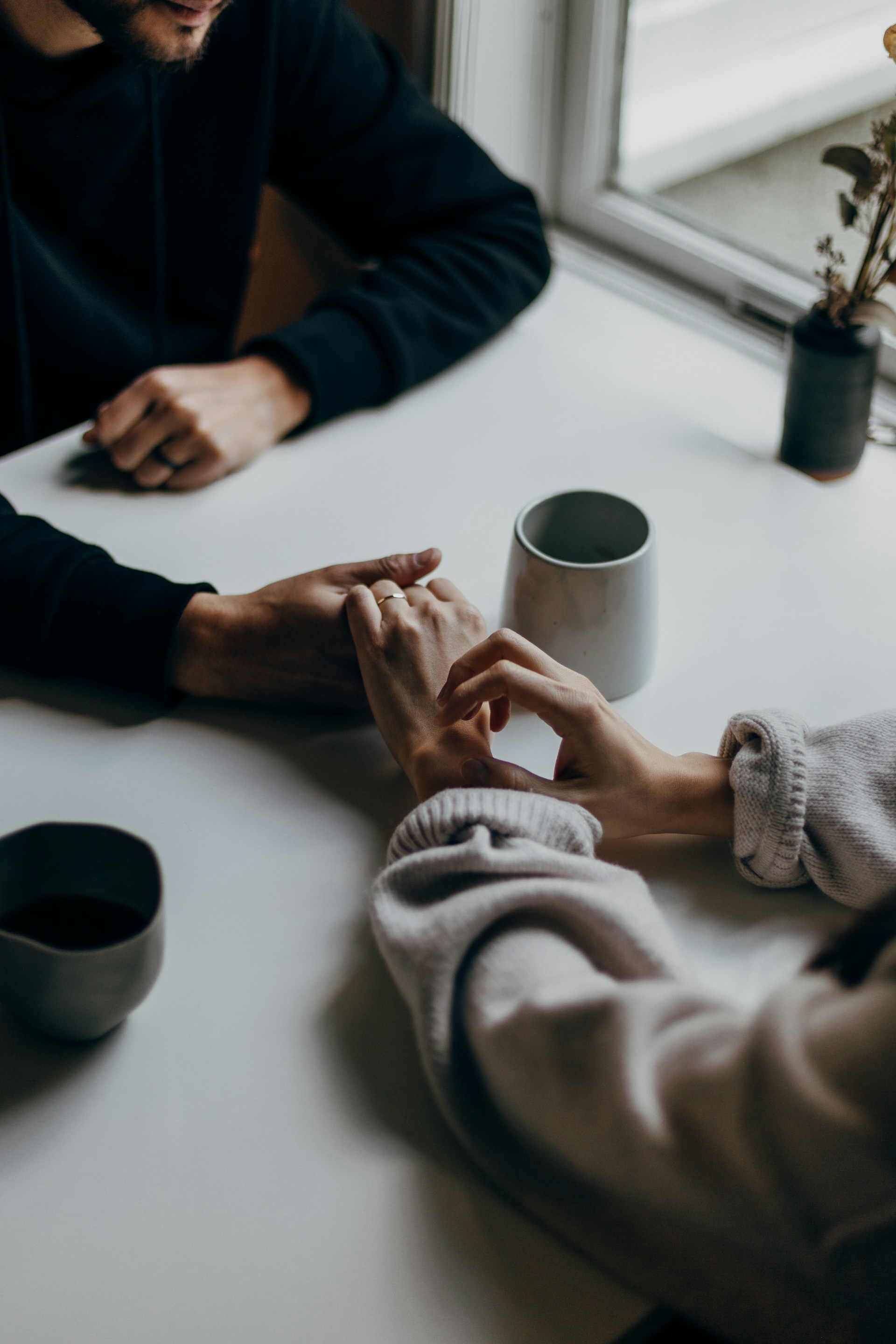 Un couple se tenant par la main à travers une table | Source : Unsplash