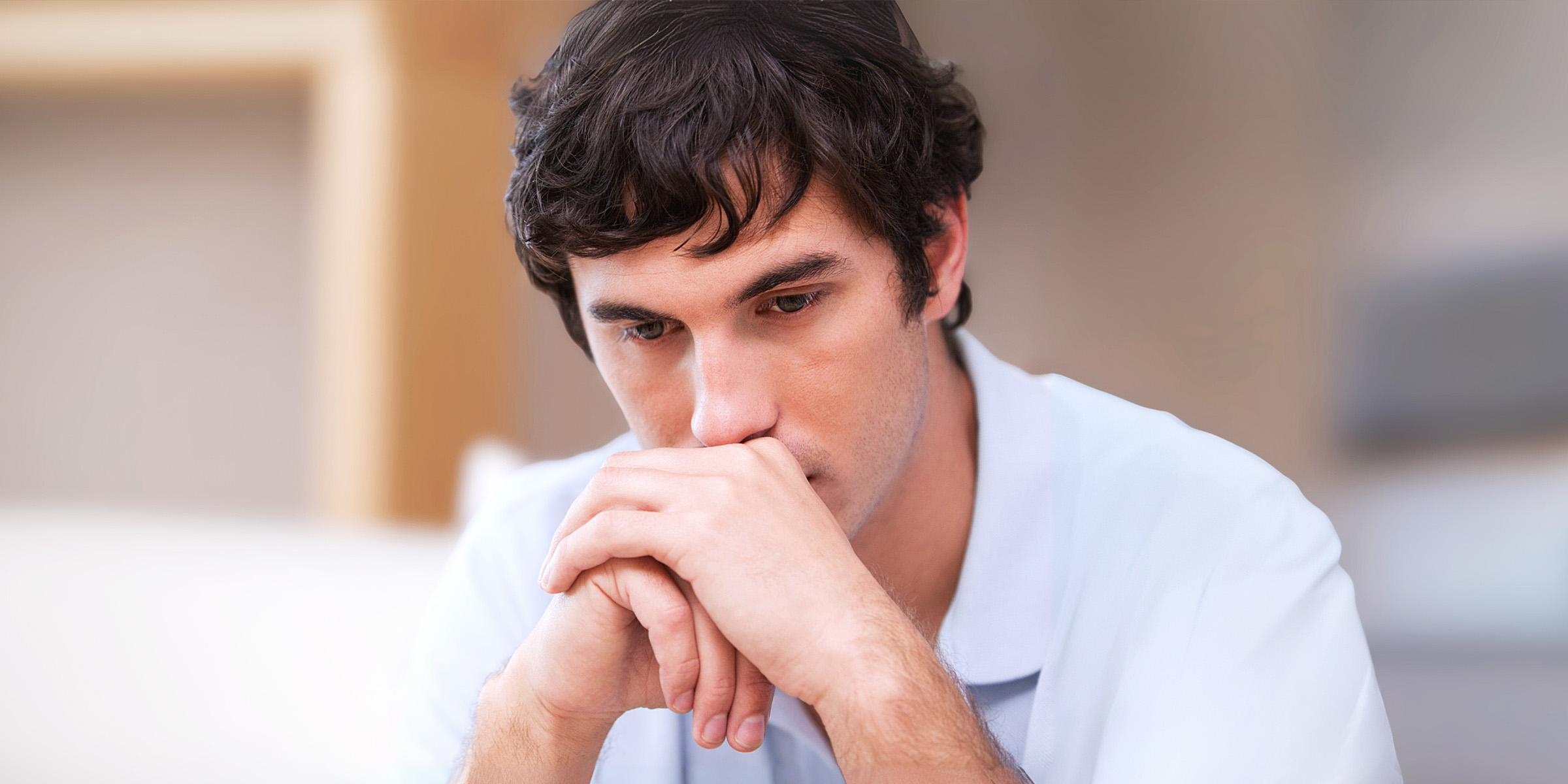 Un homme pensif assis dans un salon | Source : Shutterstock
