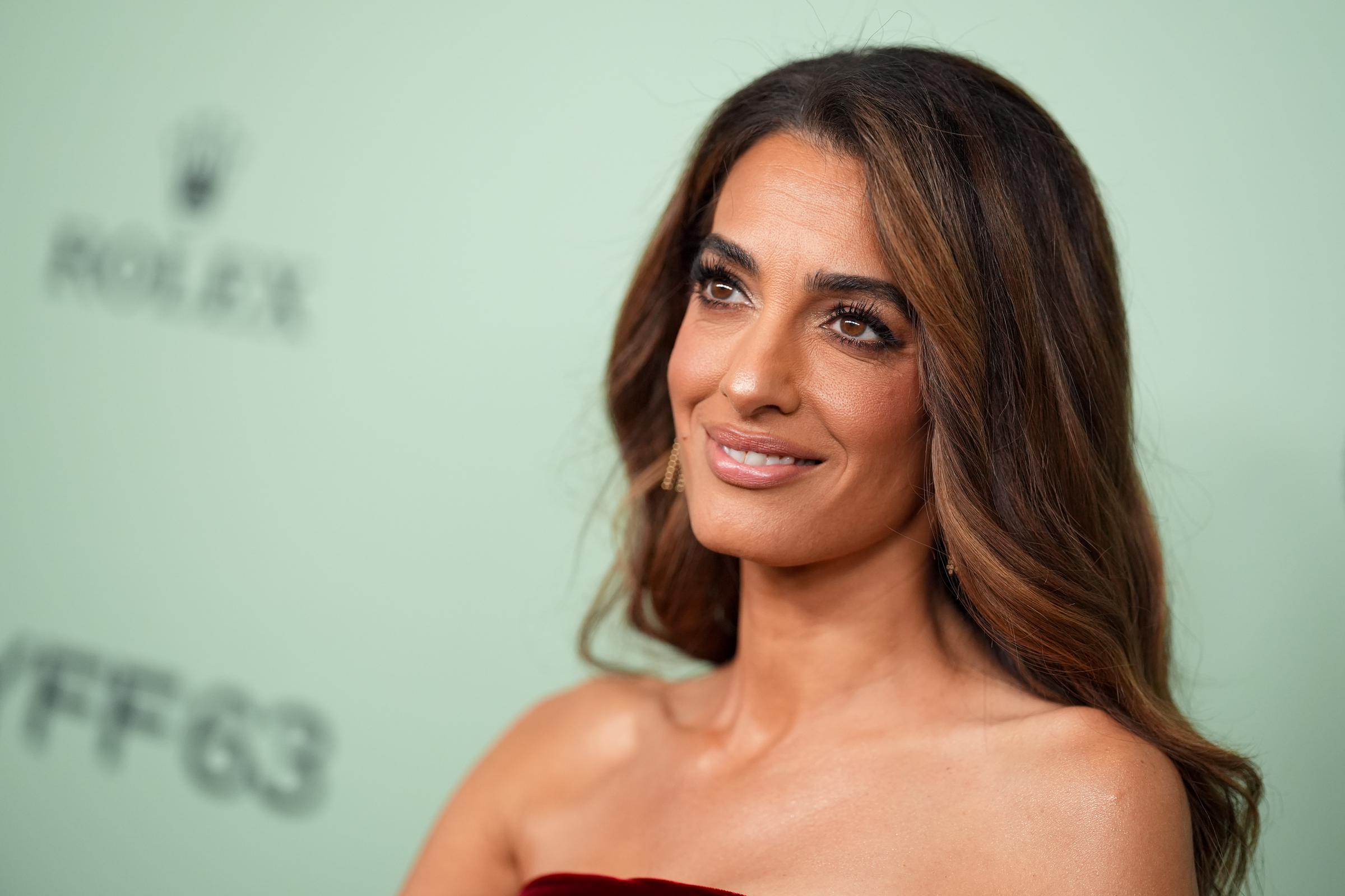Avec son élégance caractéristique, Amal Clooney se tourne légèrement vers les caméras, laissant les fronces complexes et le velours somptueux de sa robe bustier parler d'eux-mêmes.