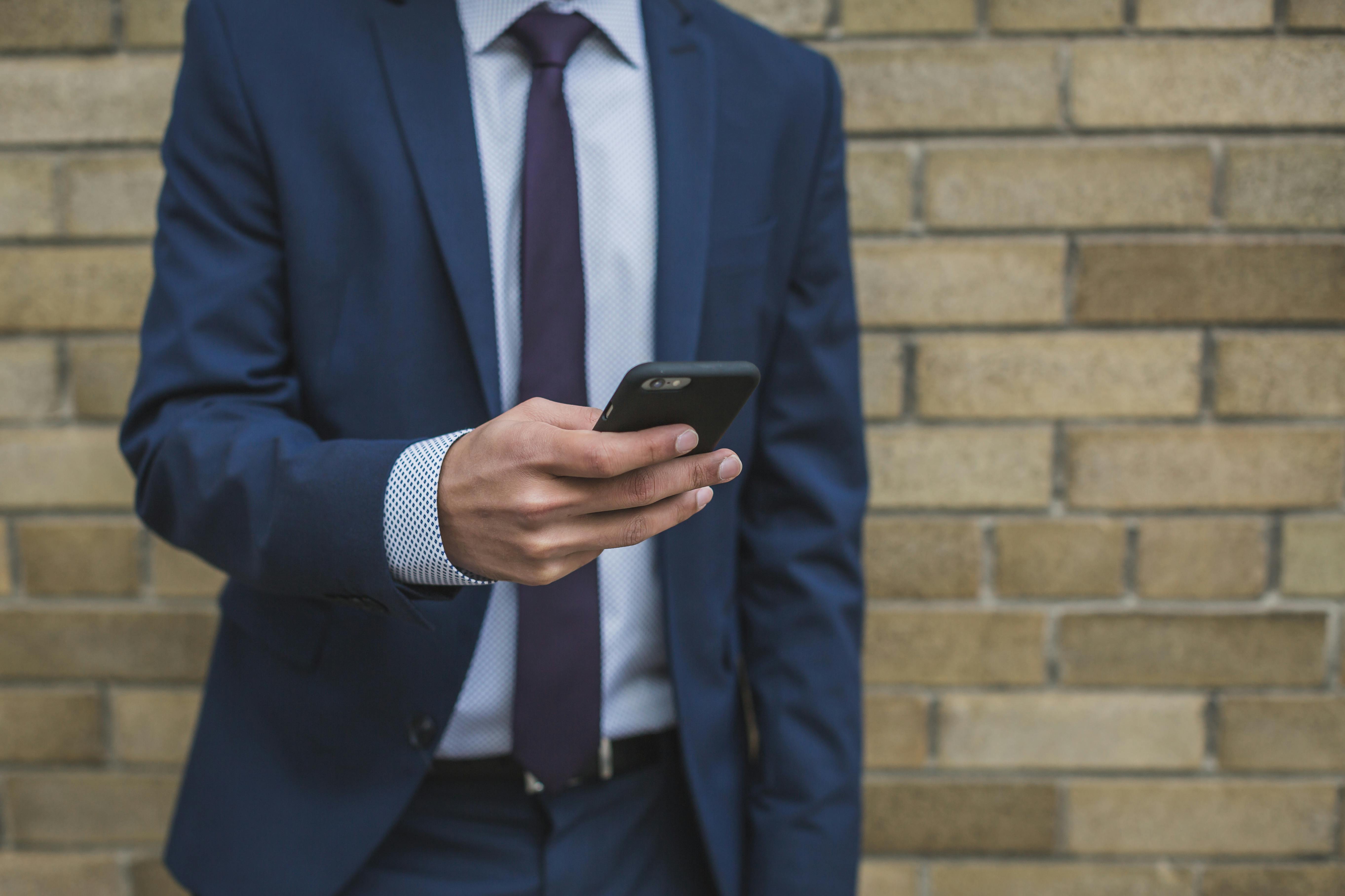 Homme en costume utilisant son smartphone | Source : Pexels