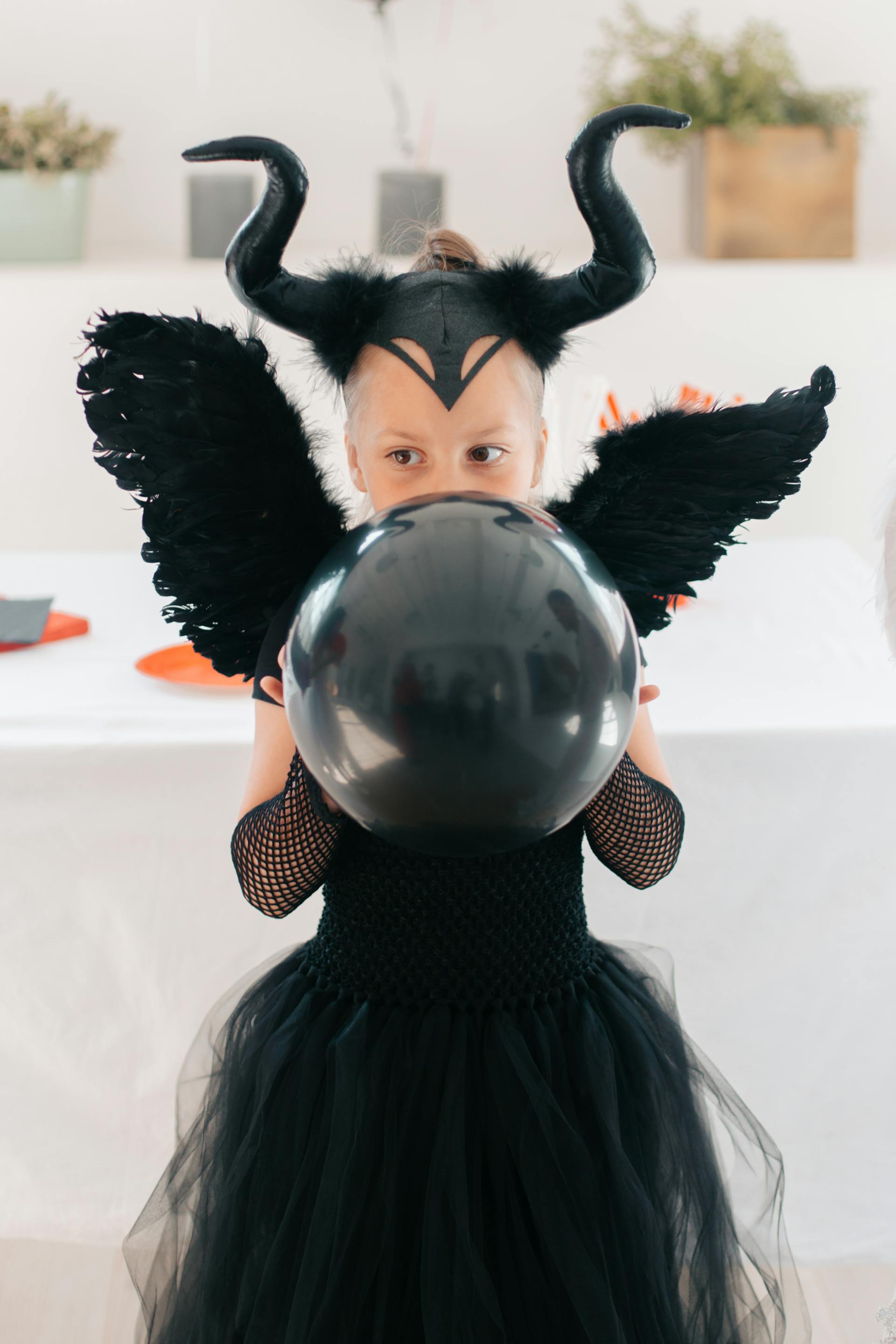 Une jeune fille portant un costume d'Halloween noir et tenant un ballon | Source : Pexels