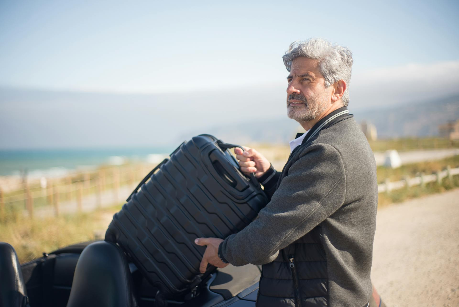 Un homme en veste grise tenant une valise | Source : Pexels