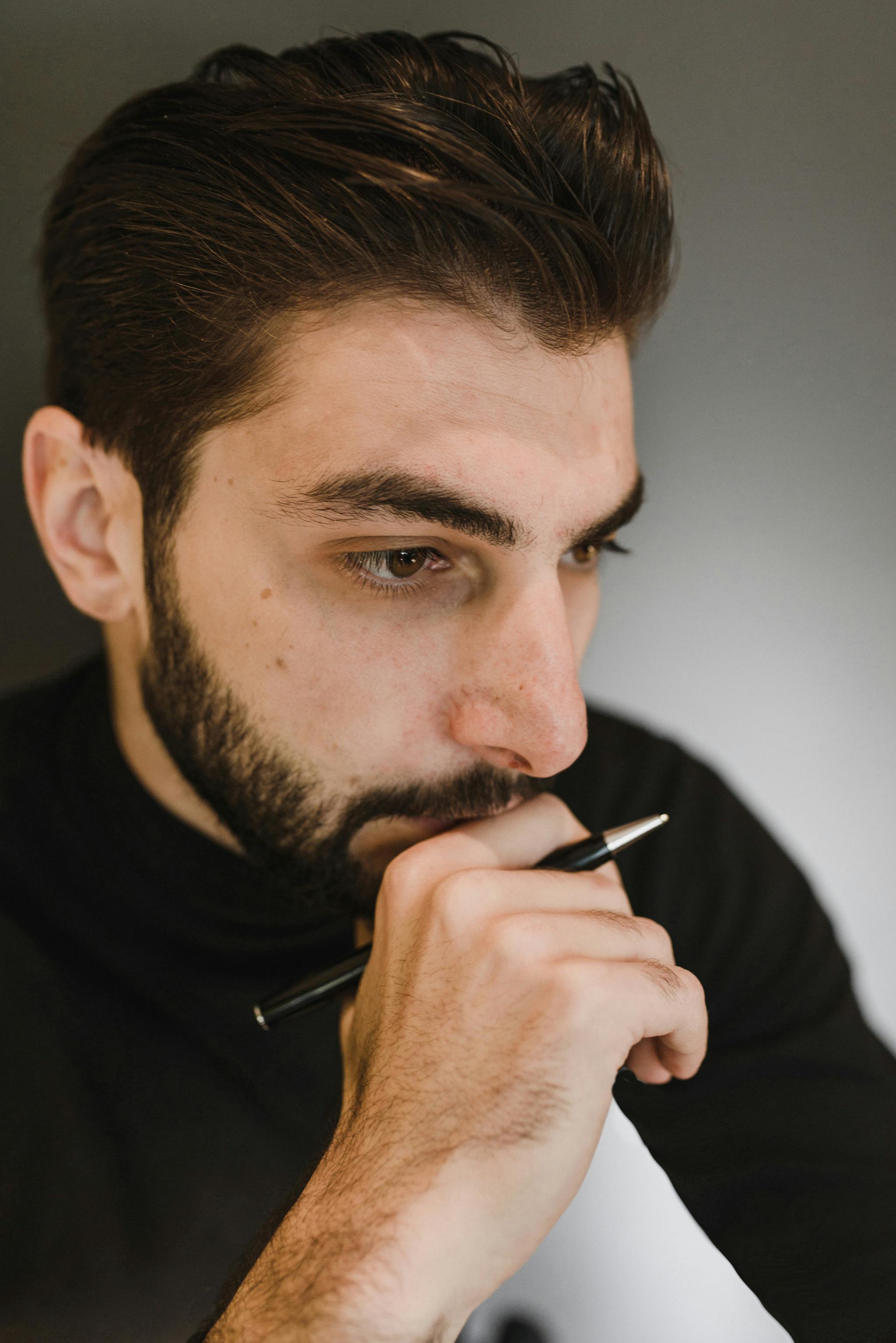 Un homme tenant un stylo tout en réfléchissant | Source : Pexels