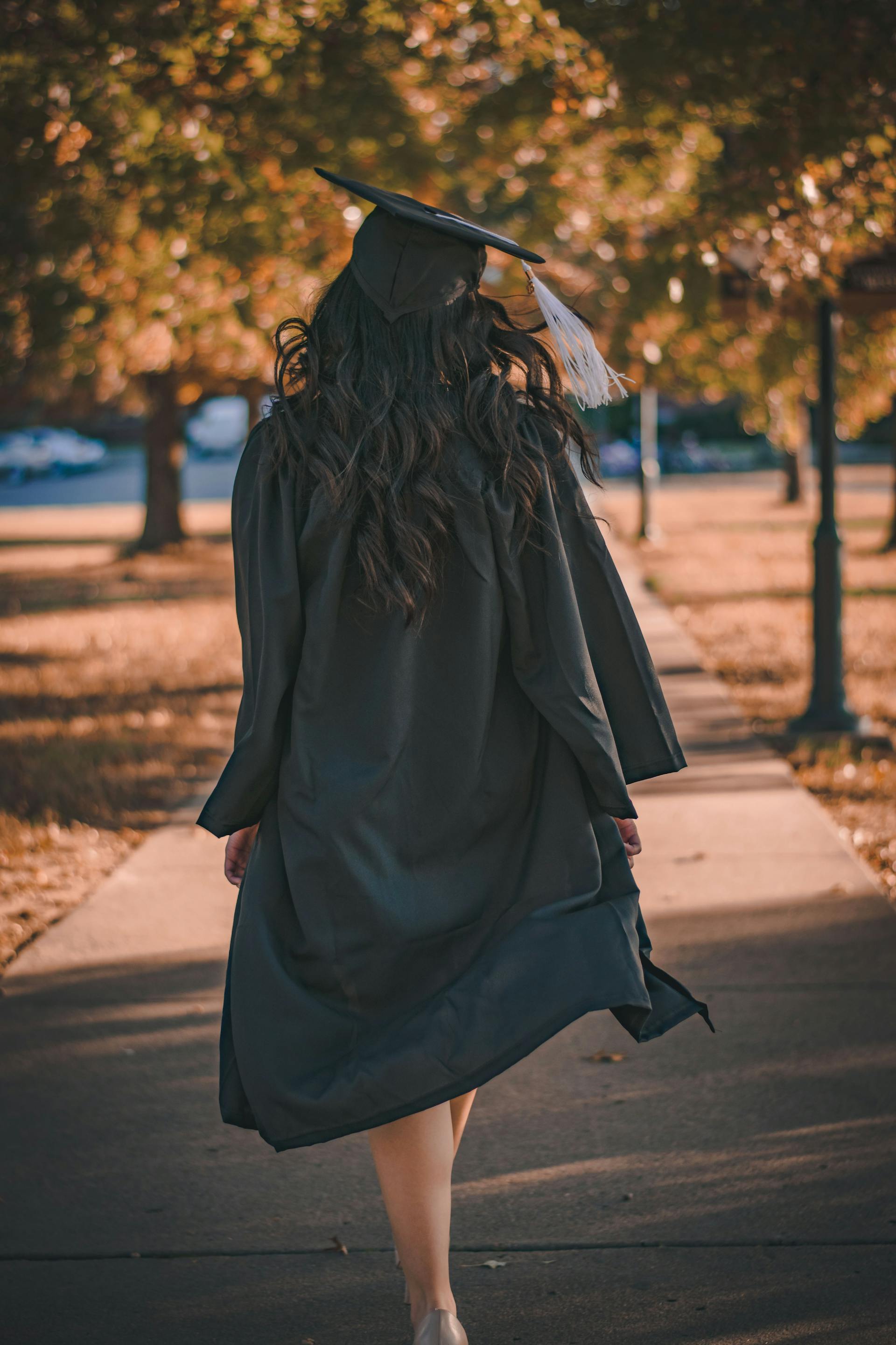 Une femme portant un chapeau et une toge marchant sur un chemin | Source : Pexels