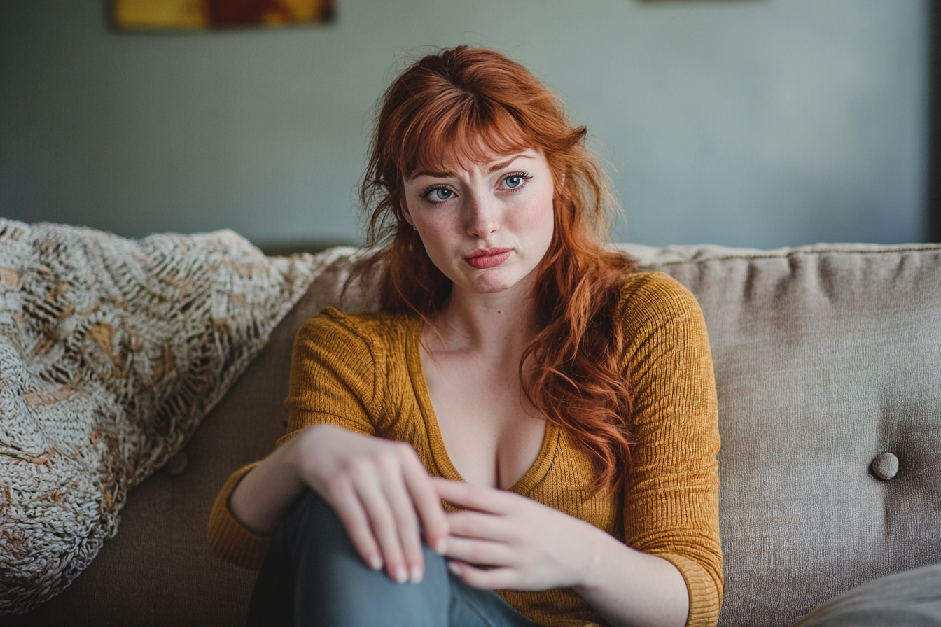 Une femme triste assise sur un canapé dans un salon | Source : Midjourney