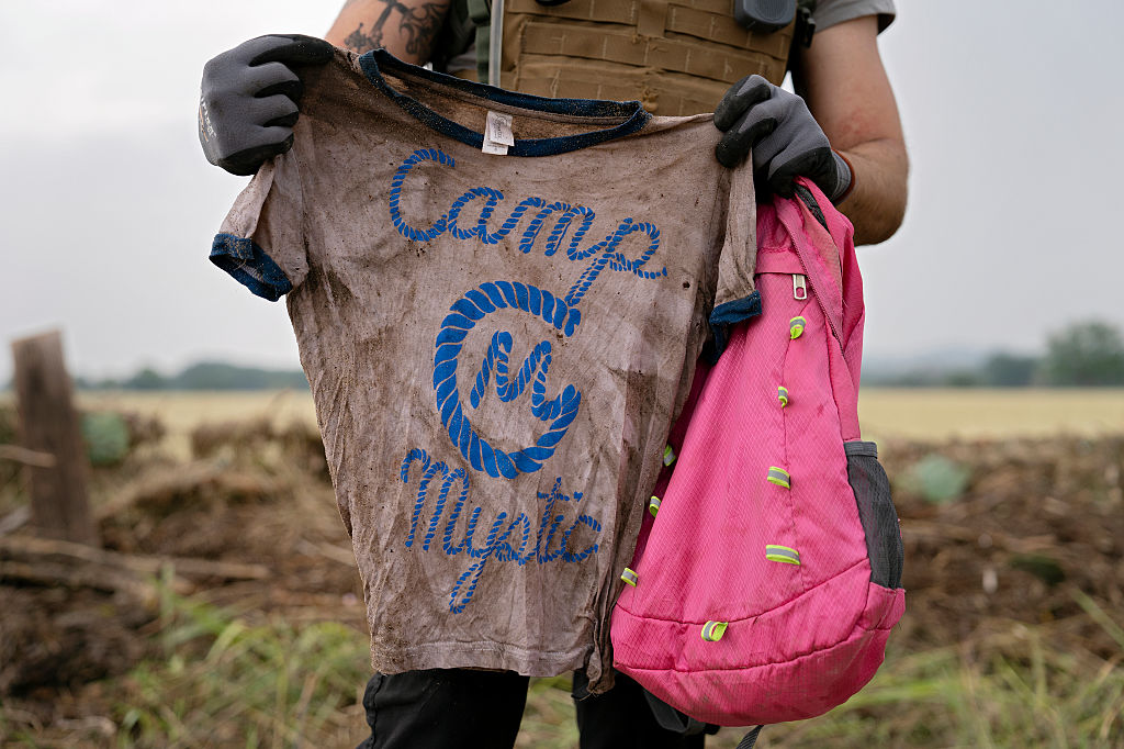 Un secouriste avec un T-shirt et un sac à dos portant les mots Camp Mystic à Comfort, Texas, le 6 juillet 2025. | Source : Getty Images