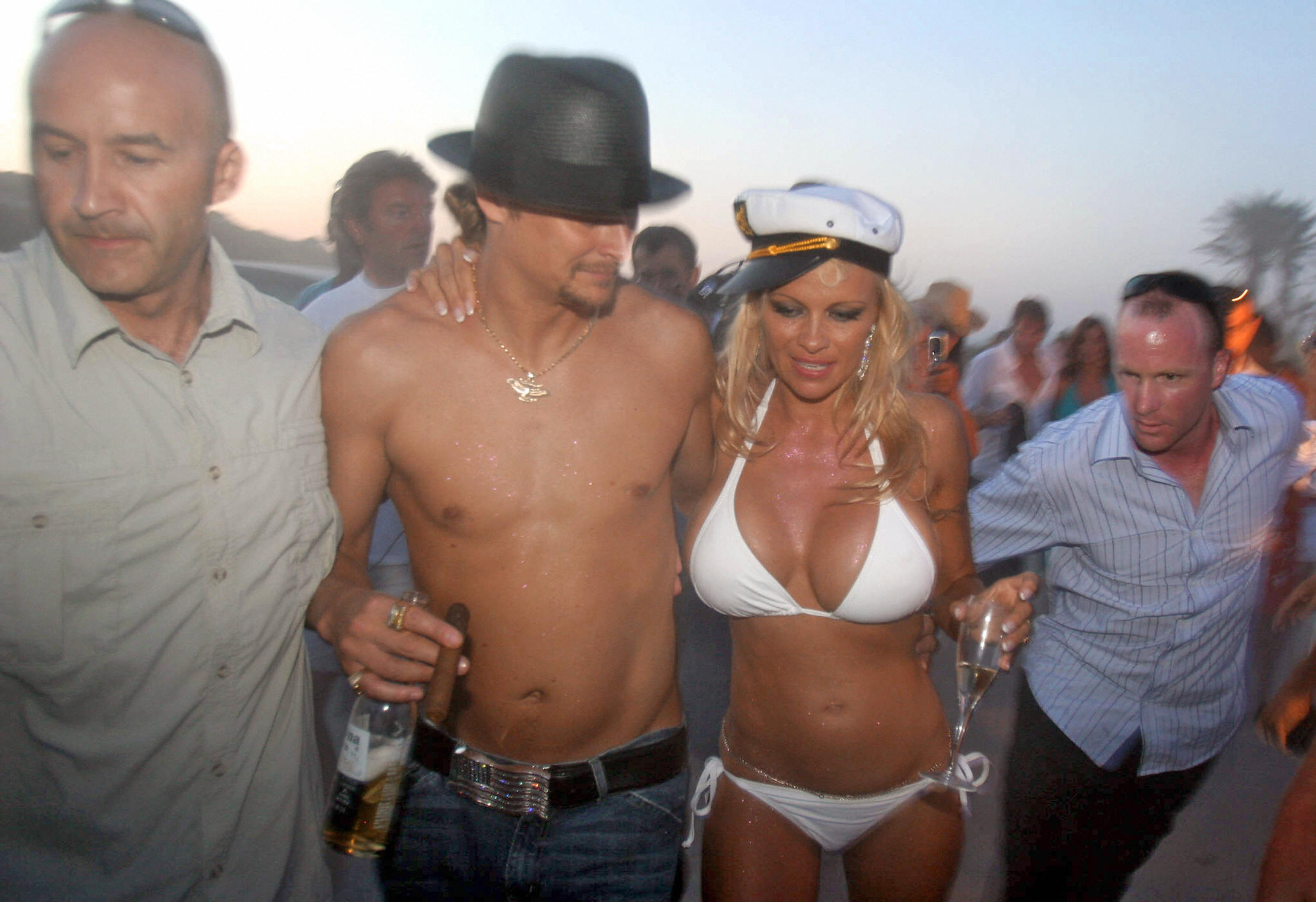 Rock et Anderson photographiés parmi la foule lors de leur mariage sur la plage, le 29 juillet 2006. Entourée de spectateurs, Anderson tenait une flûte de champagne, marchant bras dessus bras dessous avec son nouveau mari, quelques mois seulement avant leur séparation. Cependant, en raison d'un délai d'attente de six mois, aucun des deux ne pouvait se remarier avant la fin du mois de mai.