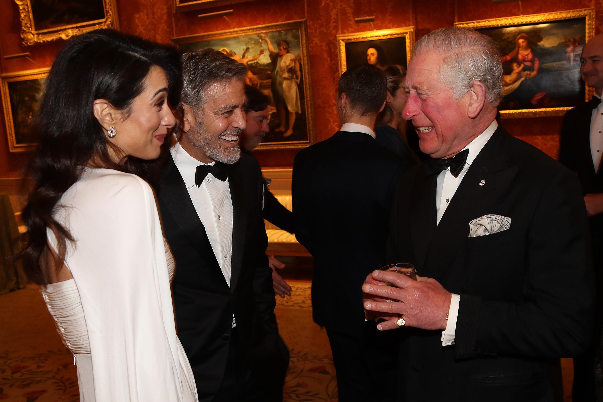 Amal et George Clooney parlent et rient avec le roi Charles III, alors prince Charles | Source : Getty Images