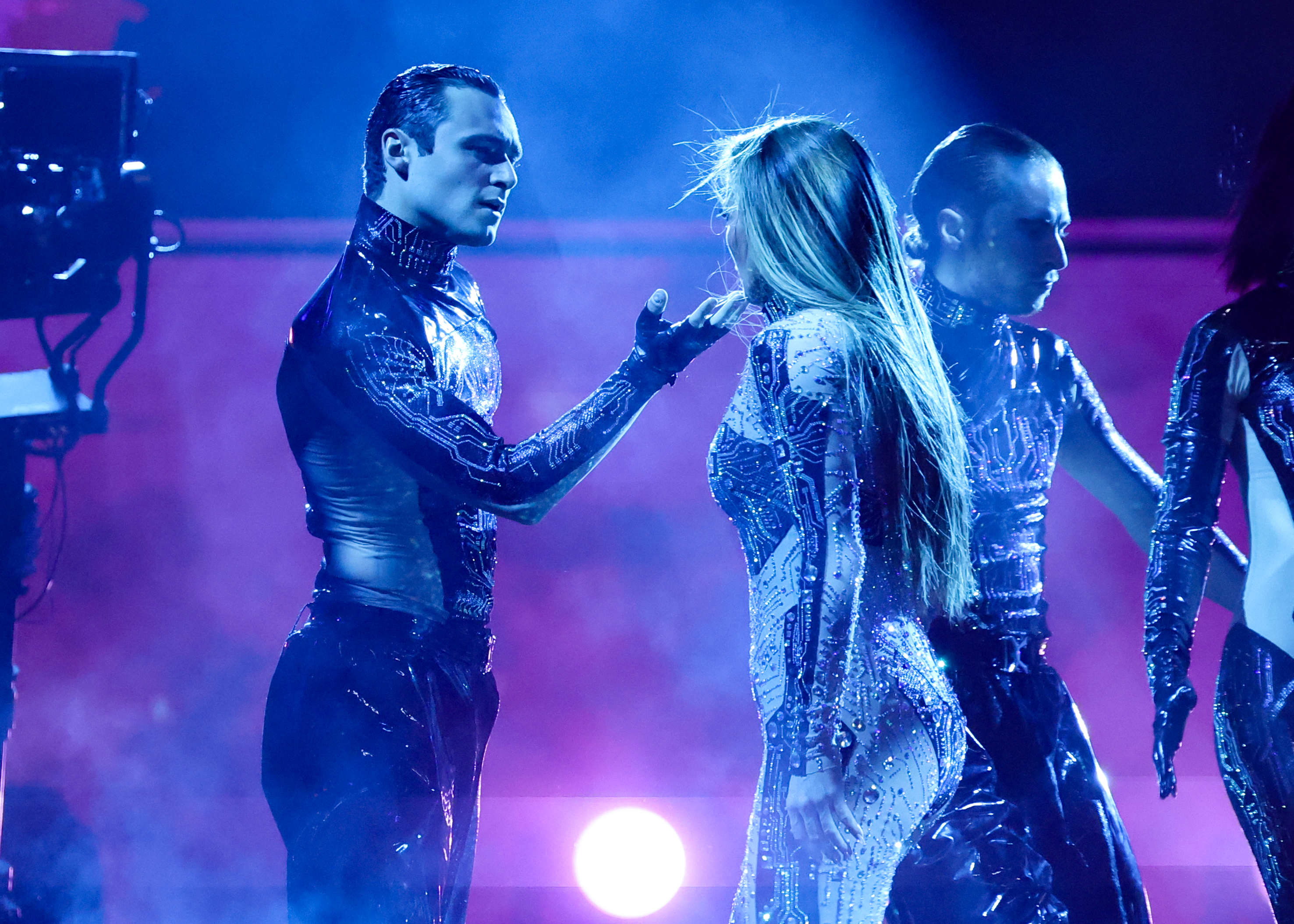 Dans un face-à-face intense et intime, Jennifer Lopez et un danseur masculin adoptent une pose puissante sous une brume bleutée, transformant son numéro aux American Music Awards 2025 au Fontainebleau Las Vegas en une fusion théâtrale de danse, de tension et de spectacle