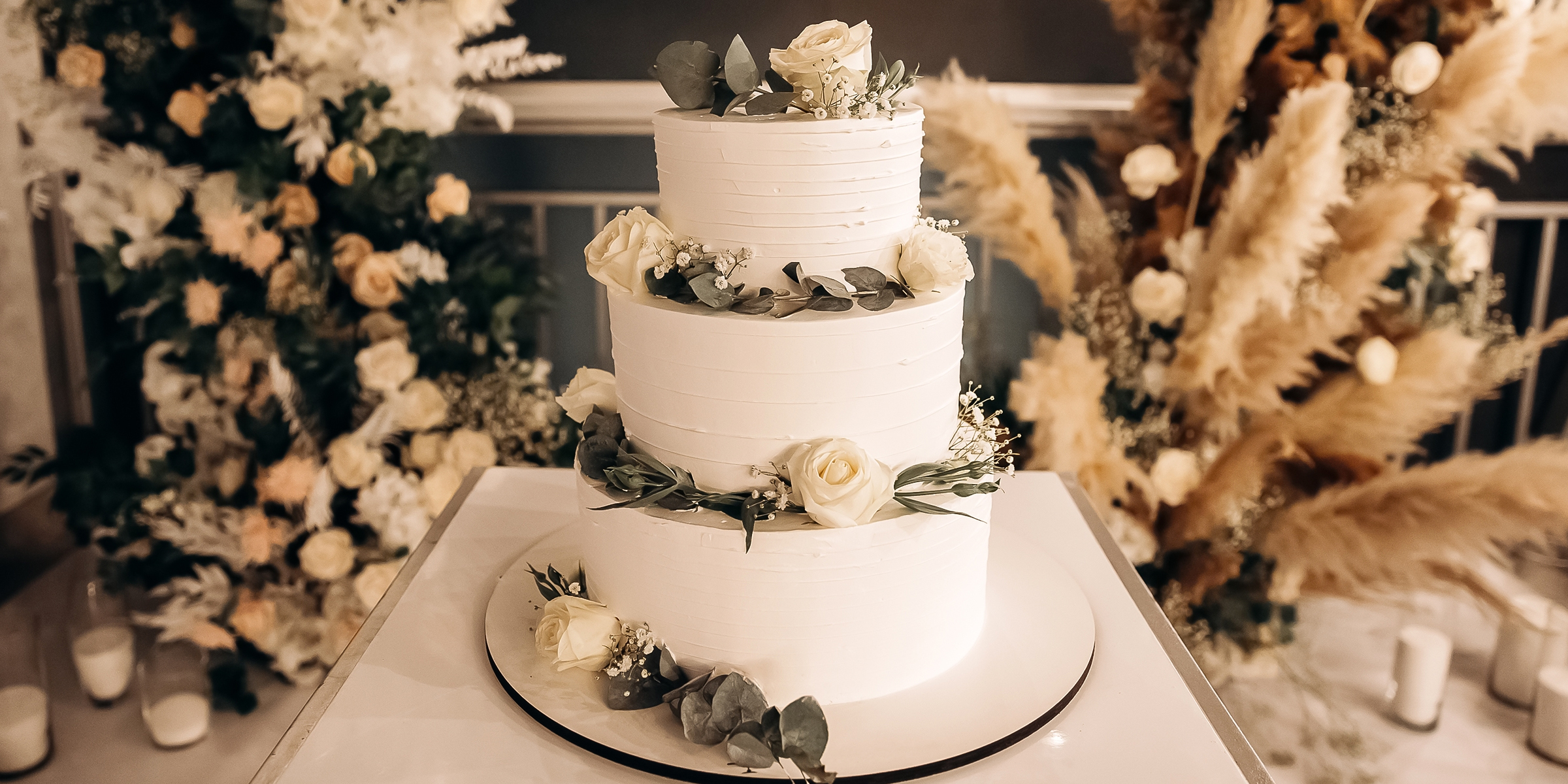 Un élégant gâteau de mariage surmonté de roses fraîches et d'une crème au beurre onctueuse | Source : Shutterstock