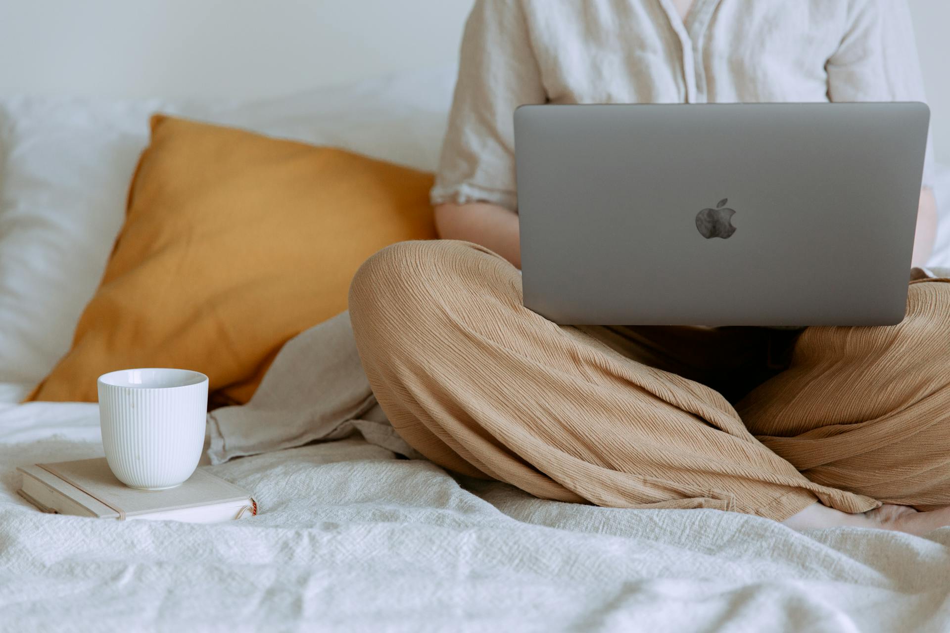 Gros plan d'une femme travaillant sur son ordinateur portable, assise dans son lit | Source : Pexels