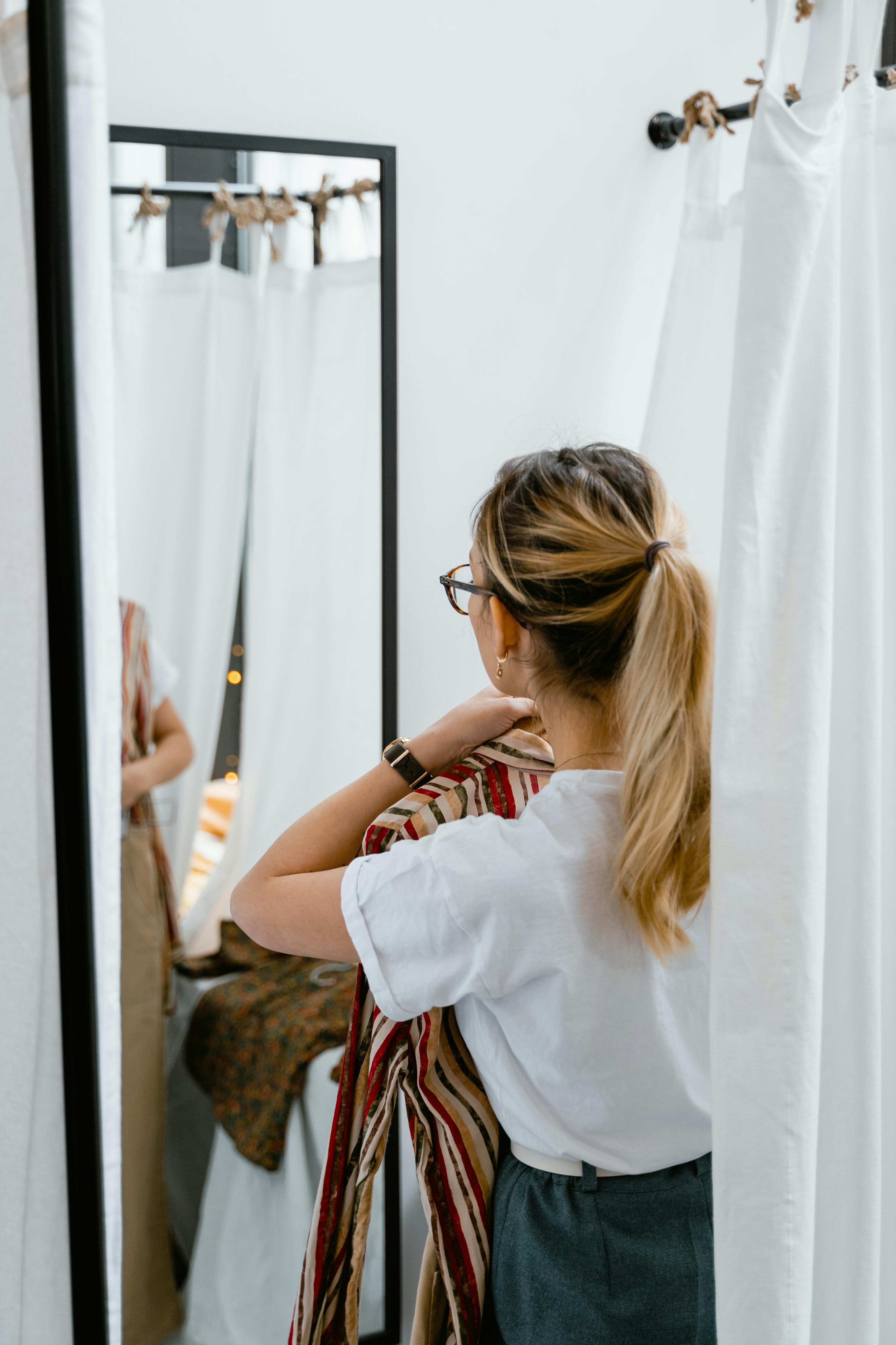Une femme tenant des vêtements dans le vestiaire | Source : Pexels