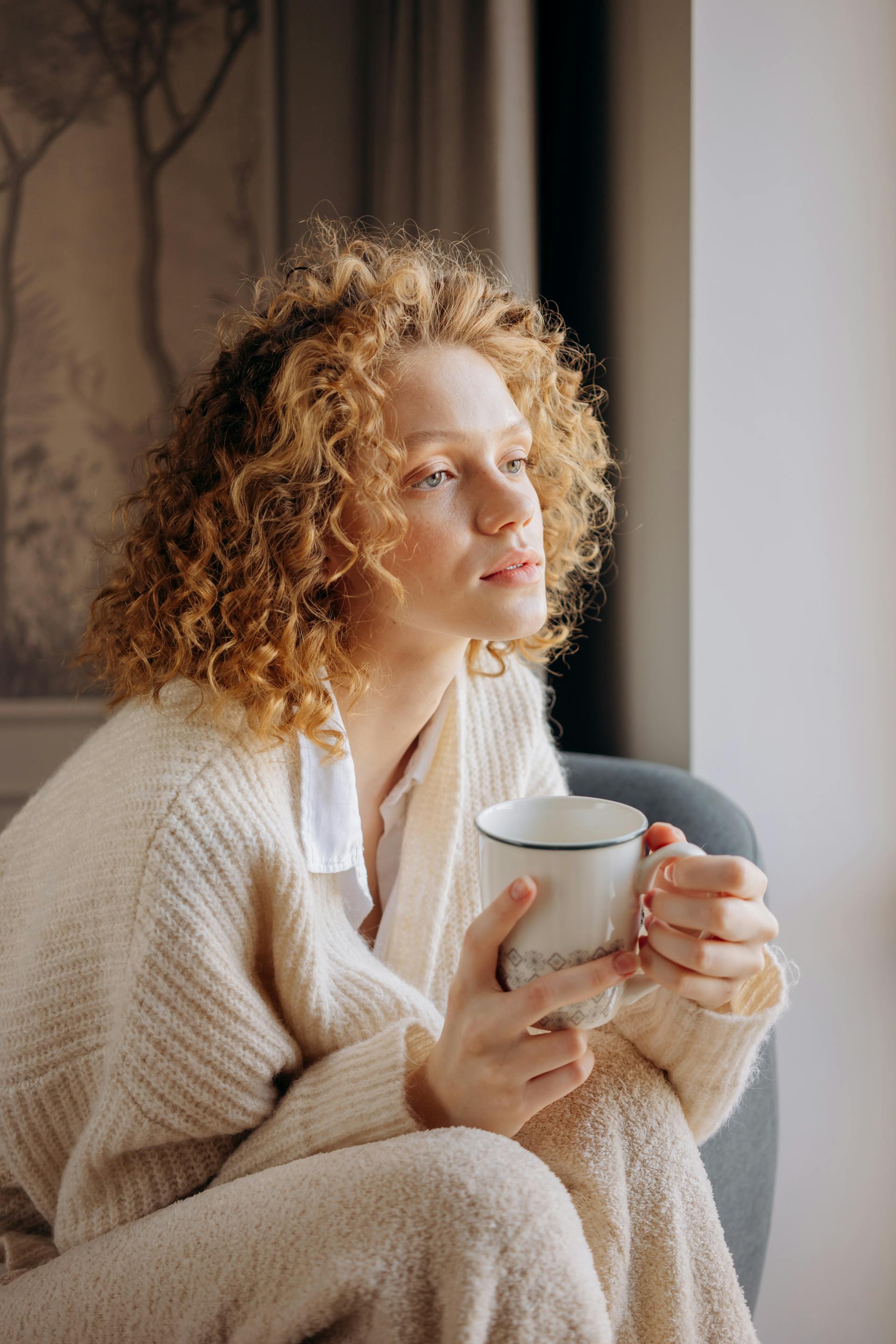 Une femme aux cheveux bouclés tenant une tasse | Source : Pexels