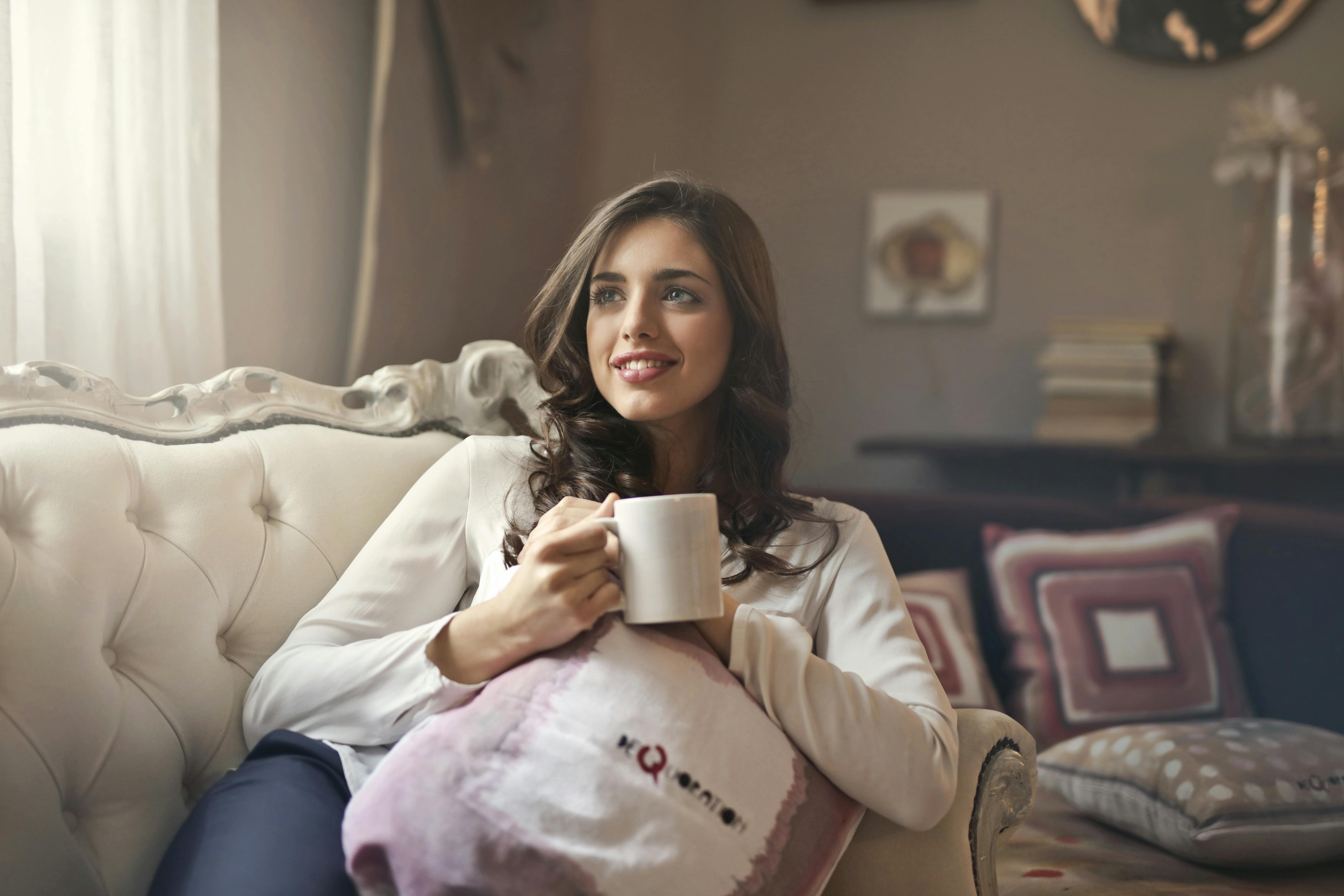 Une femme assise sur un canapé avec une tasse de thé | Source : Pexels