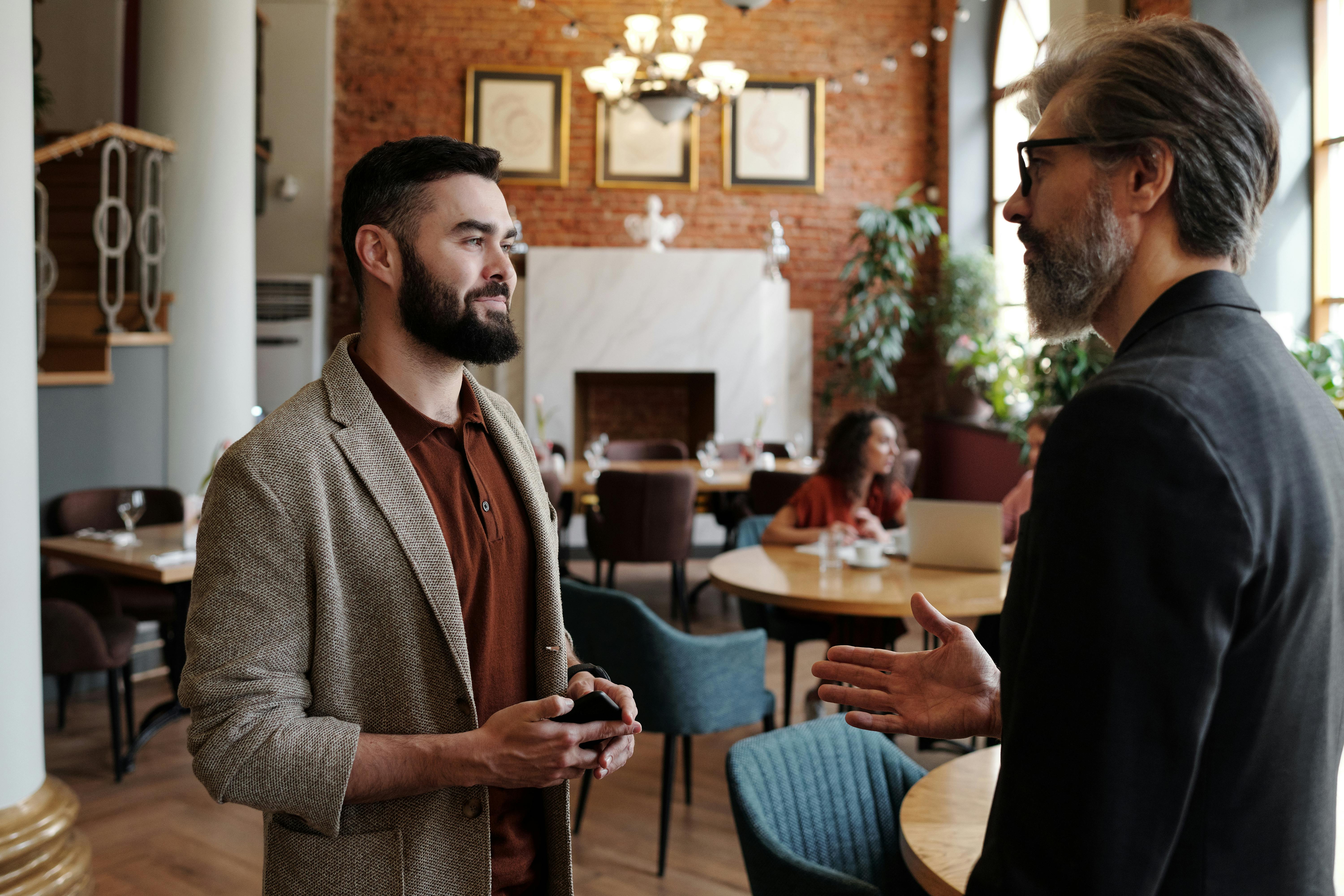 Homme âgé en veste noire parlant à un homme en veste marron | Source : Pexels