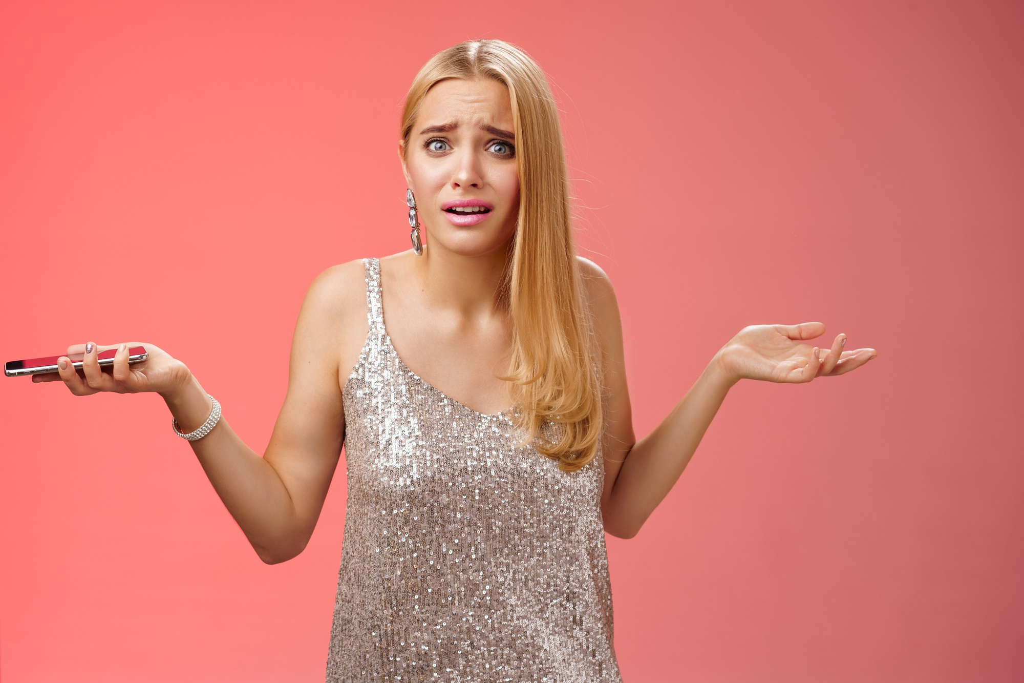 Une femme émotive tenant un téléphone tout en essayant de s'expliquer | Source : Freepik