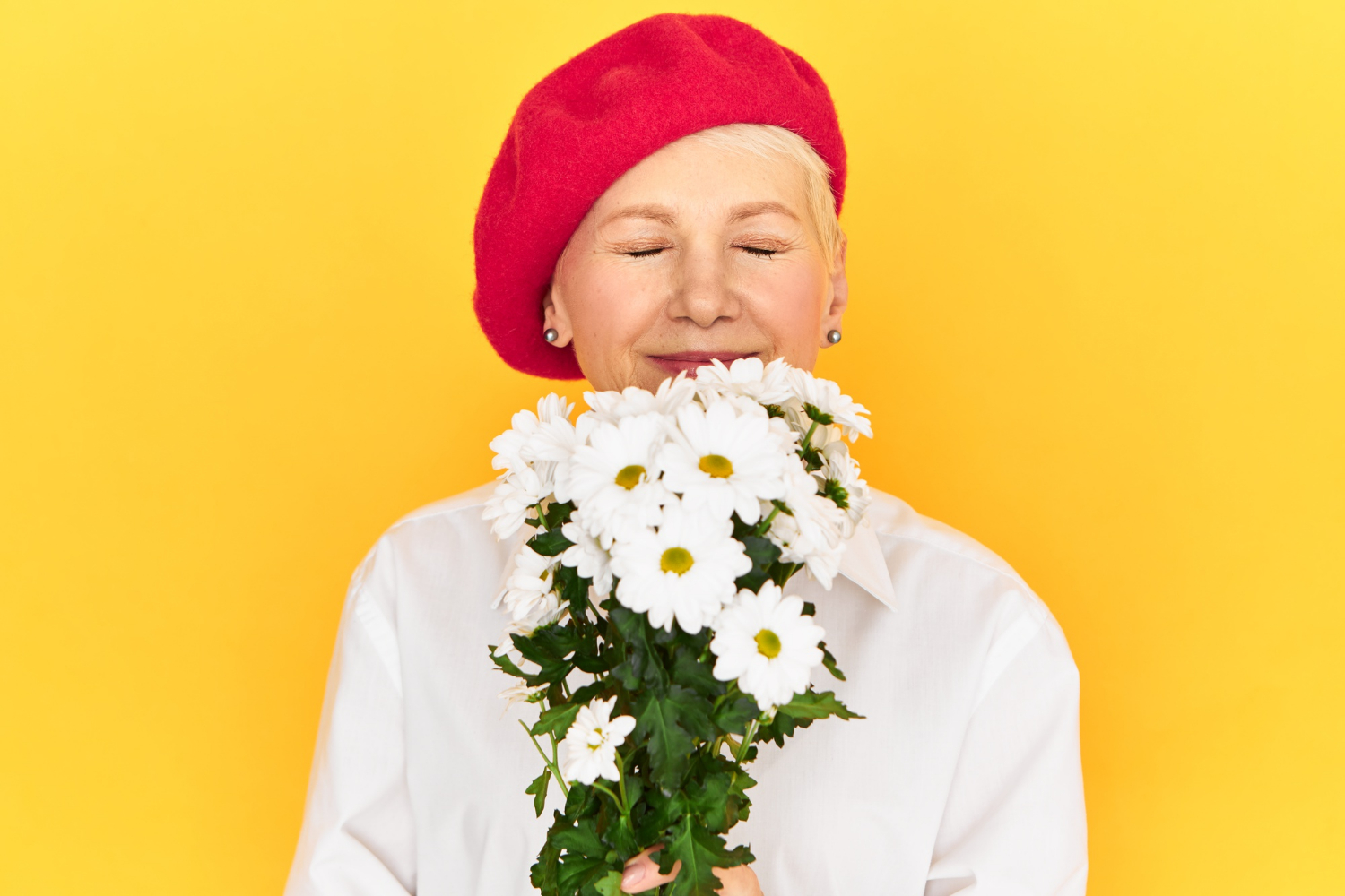 Une femme âgée tenant un bouquet de marguerites blanches | Source : Freepik
