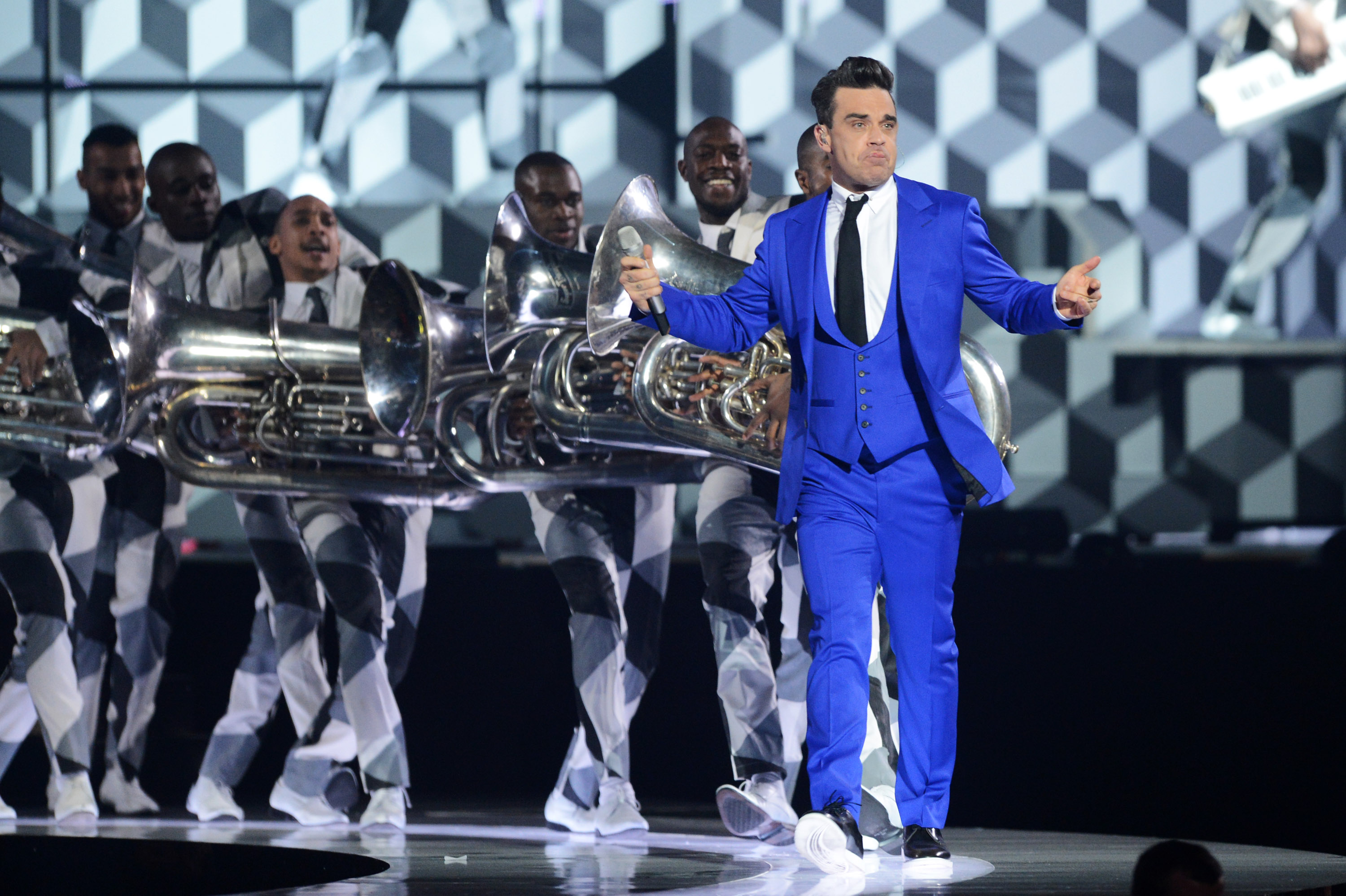 Robbie Williams aux Brit Awards 2013 le 20 février à Londres, en Angleterre, vêtu d'un costume bleu électrique saisissant. Entouré d'une fanfare aux motifs audacieux en noir et blanc, il a livré l'une des performances les plus dynamiques et énergiques de la soirée.