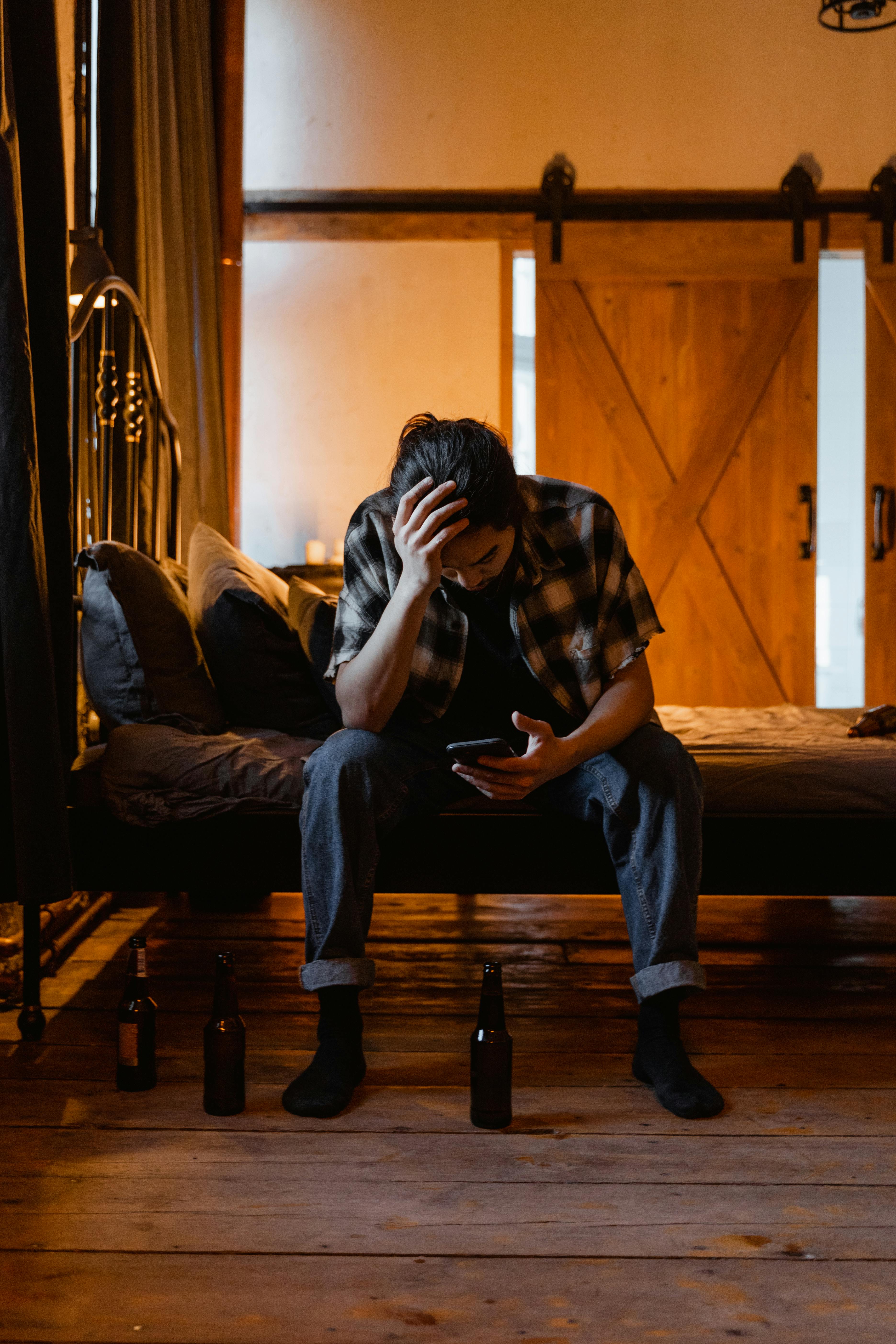 Un homme fatigué assis sur un lit | Source : Pexels
