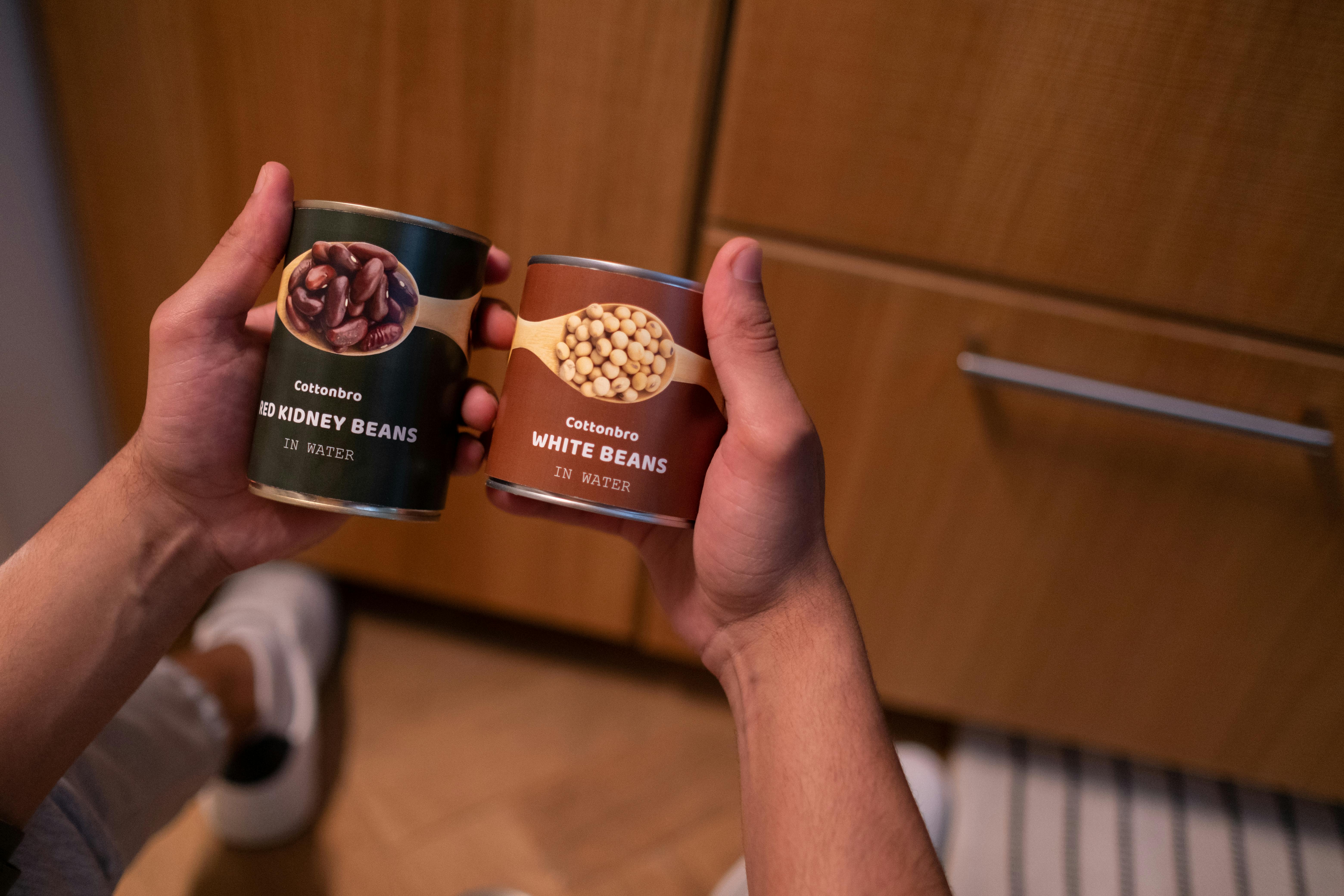 Mains tenant des boîtes de haricots | Source : Pexels