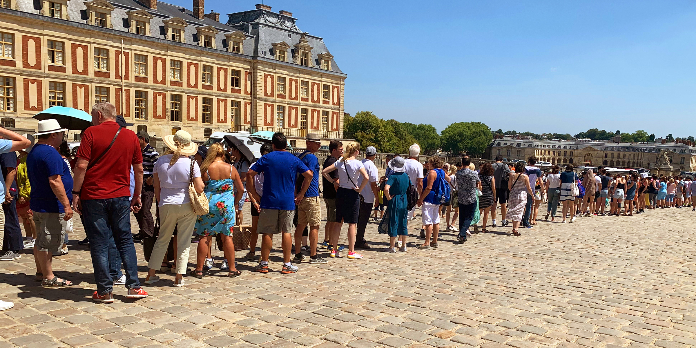 Des touristes qui attendent leurs billets ppur visiter le château de Versailles | Source : Getty Images