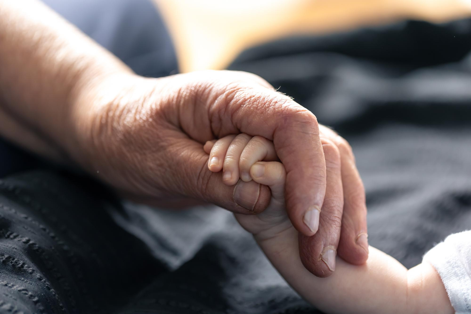 Une personne âgée tenant la main d'un bébé | Source : Freepik