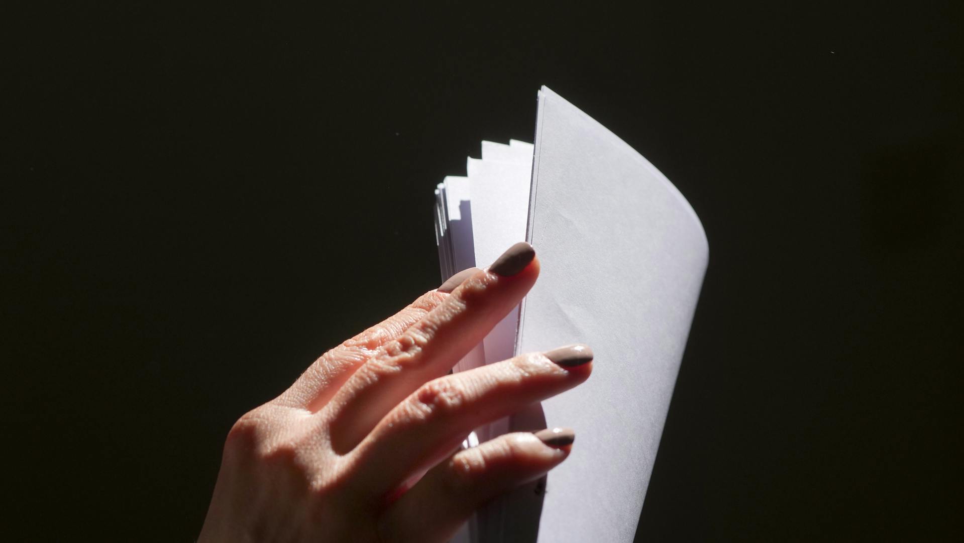 Gros plan sur une femme qui feuillette des feuilles de papier | Source : Pexels