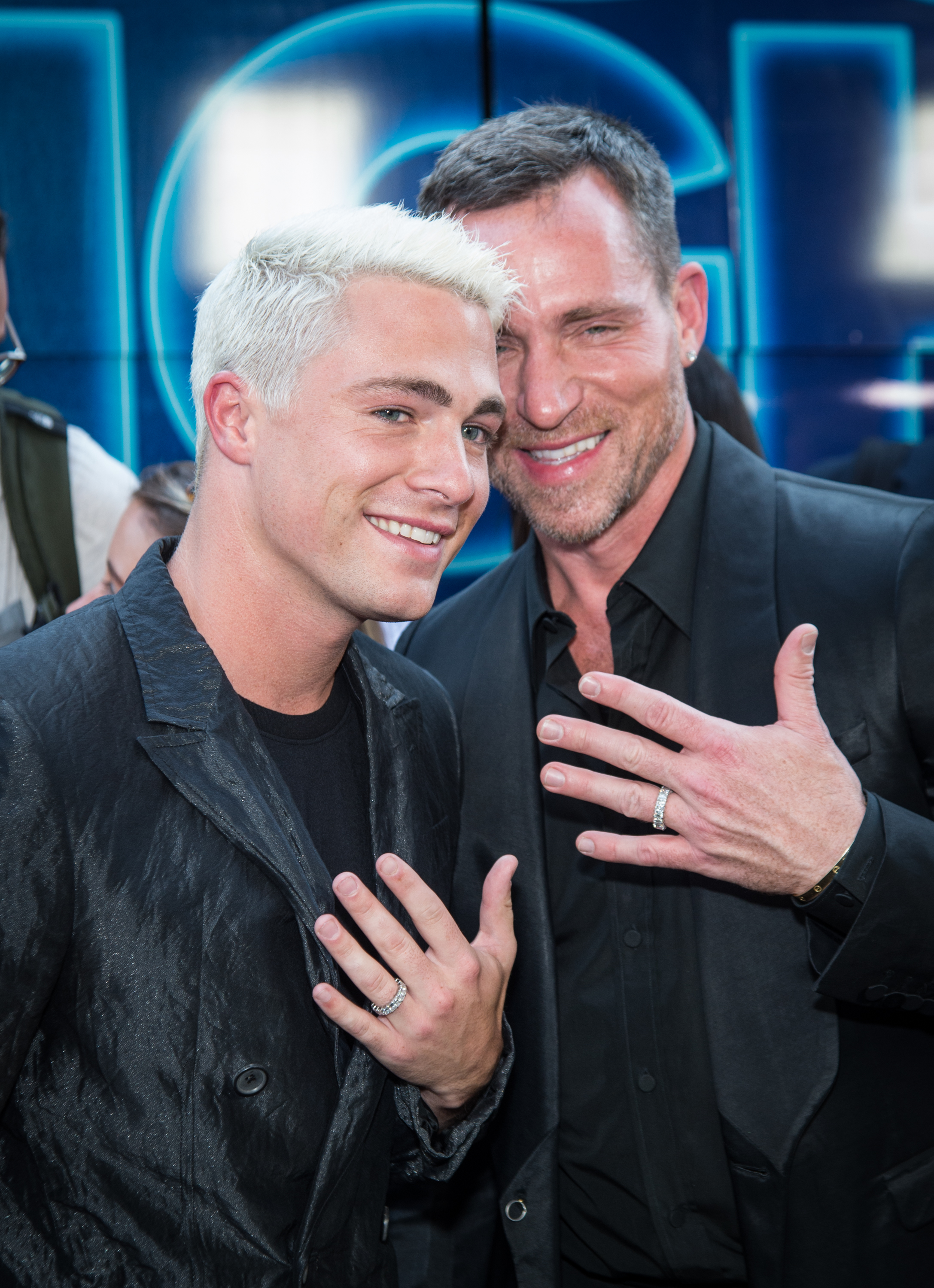 Colton Haynes et Jeff Leatham exhibent leurs alliances lors de la première du film « Rough Night » le 12 juin 2017 à New York. Haynes porte un costume noir texturé et arbore une chevelure blond platine, tandis que Leatham se tient à ses côtés dans un ensemble noir. Tous deux sourient en posant, les mains levées.