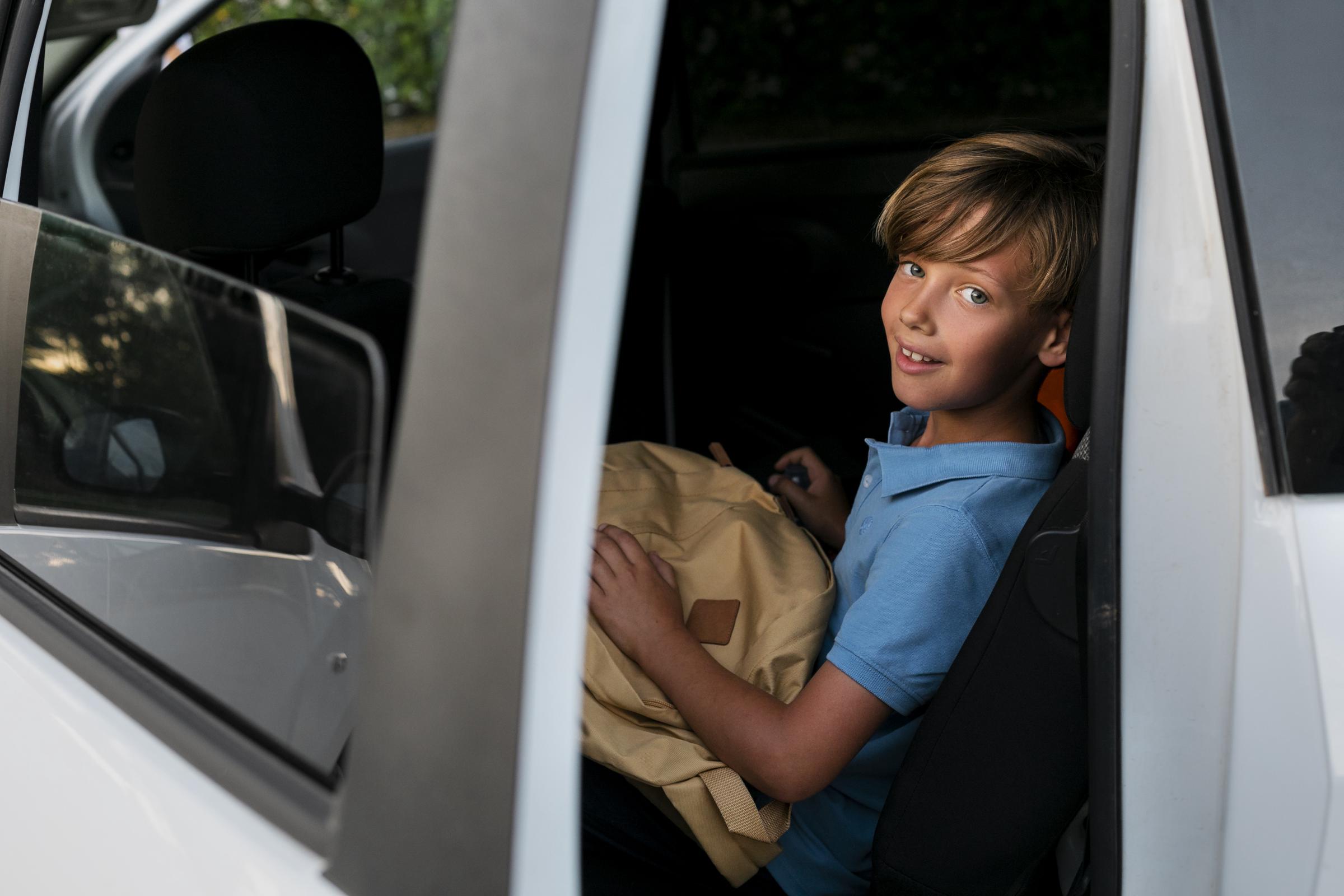 Un garçon souriant dans une voiture | Source : Freepik