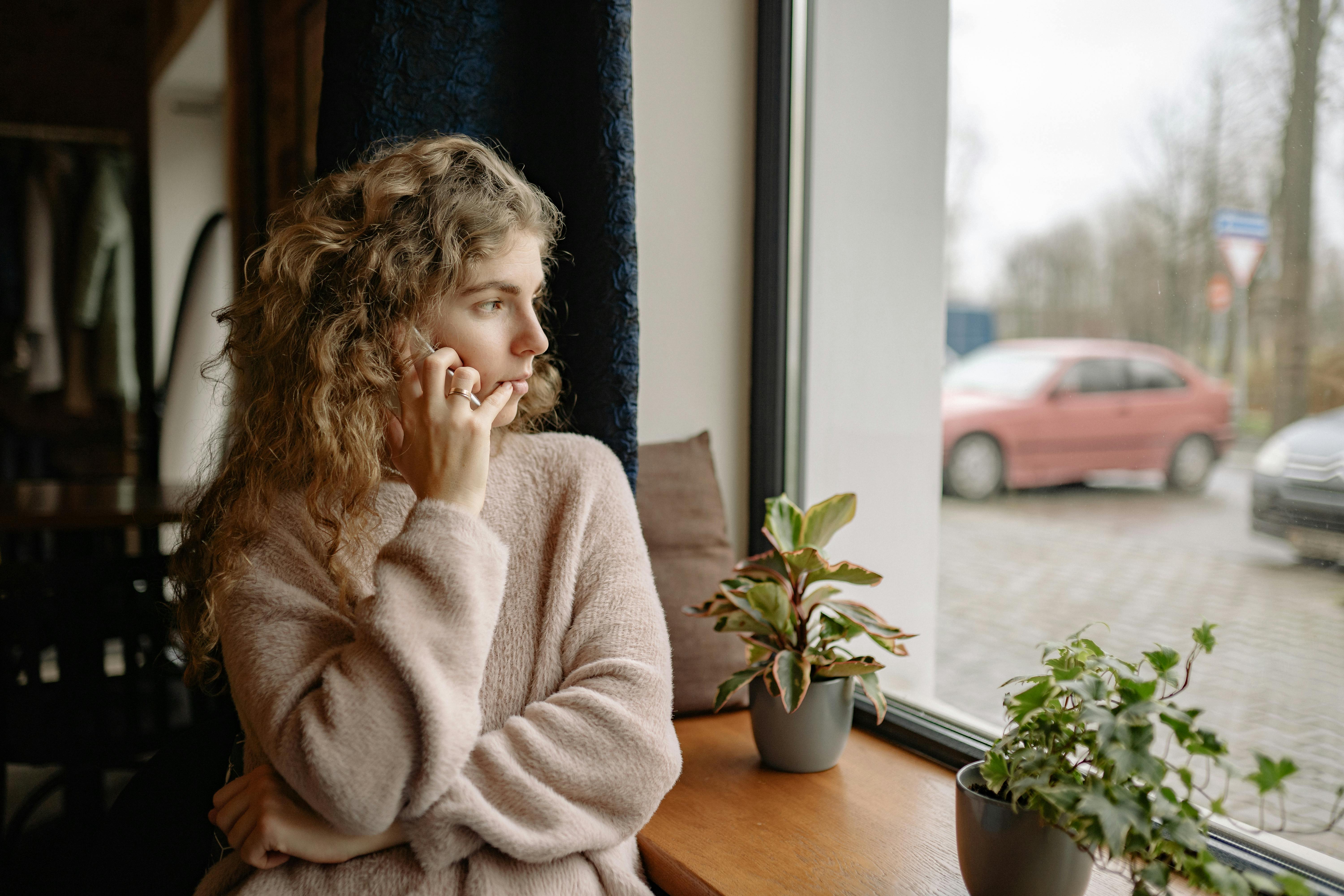 Femme parlant au téléphone tout en regardant à l'extérieur | Source : Pexels